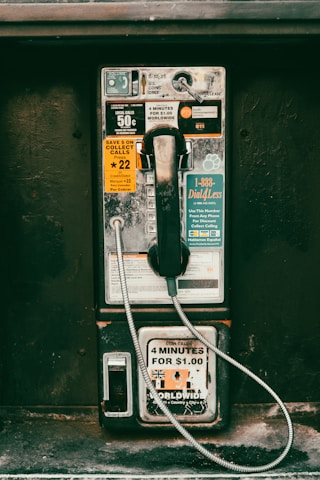 An old fashioned pay phone sitting on the side of a building