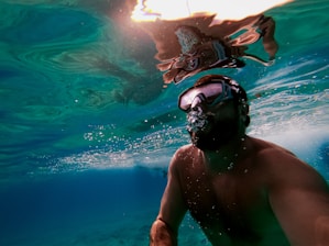 A man swimming in the ocean with a mask on