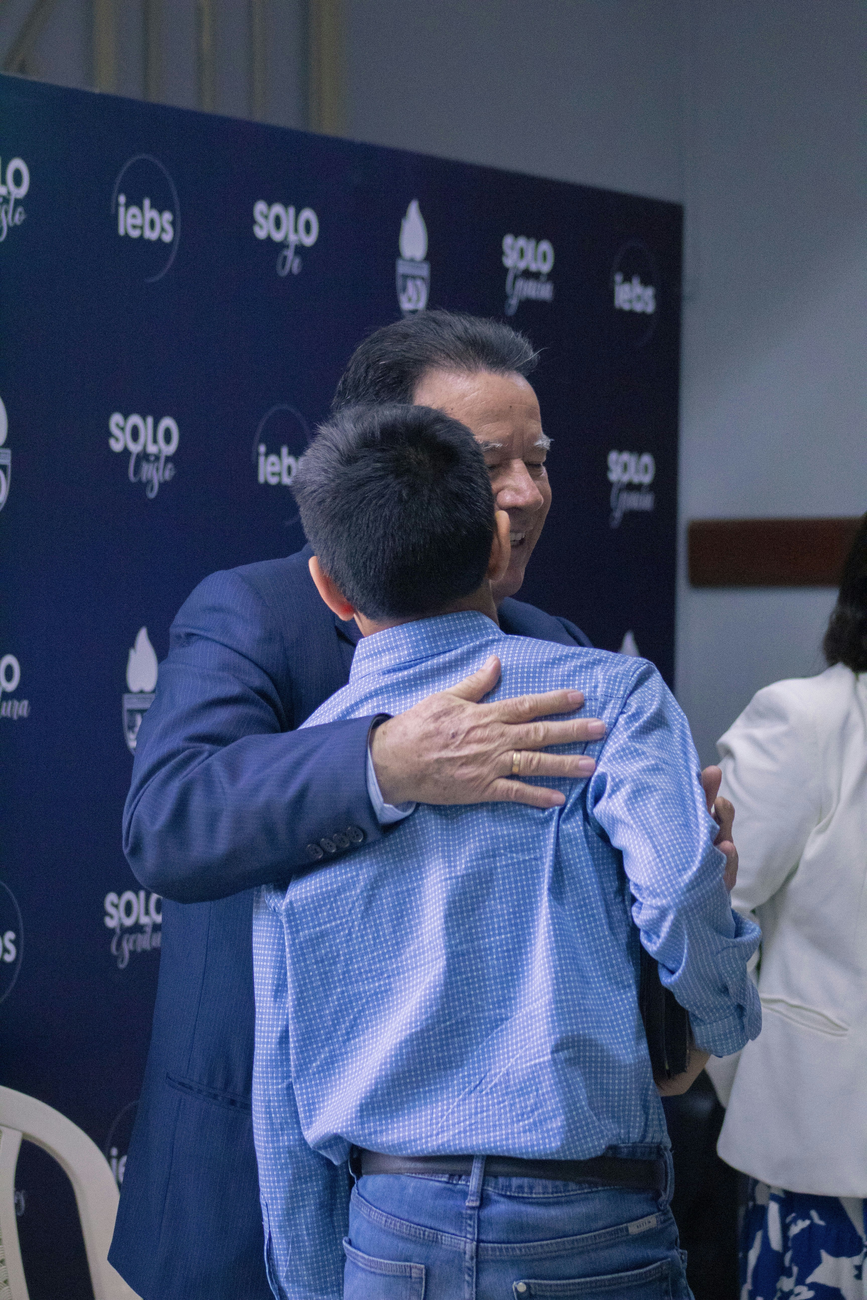 A man hugging a woman in front of a blue backdrop