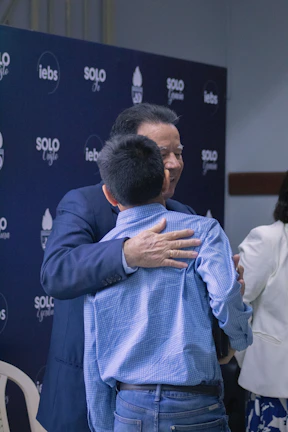 A man hugging a woman in front of a blue backdrop
