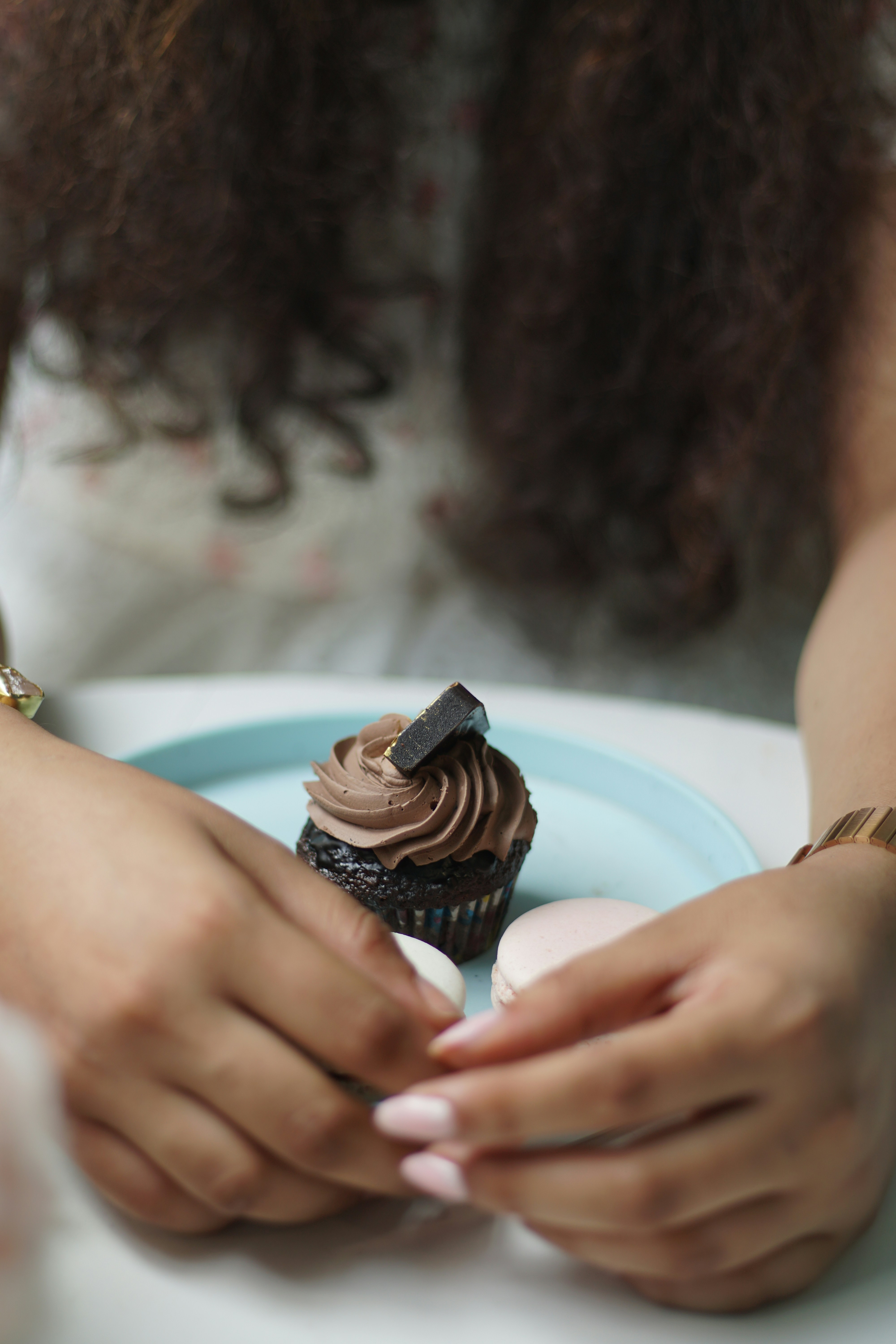 A woman sitting at a table with a plate of cupcakes