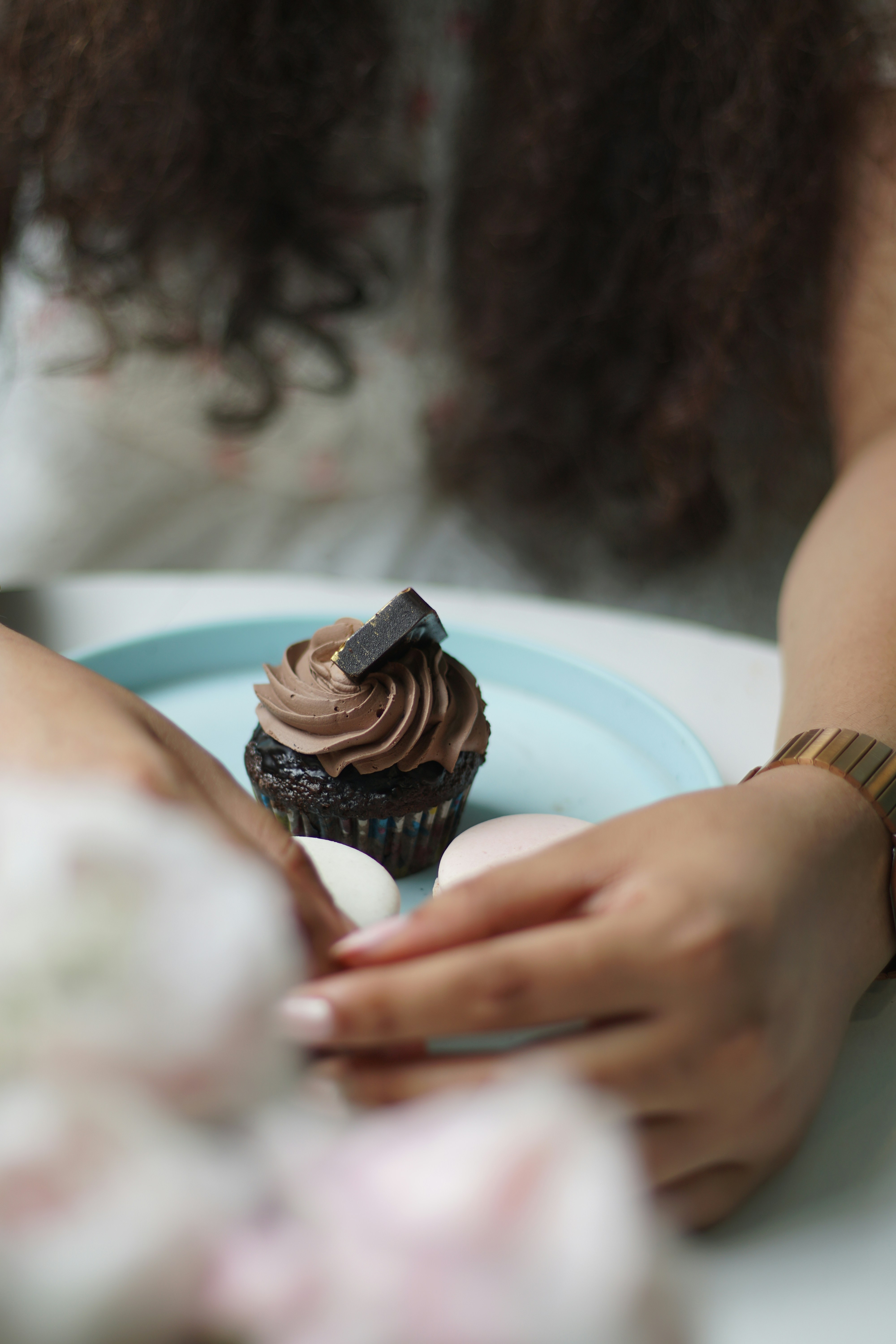 A woman holding a plate with a chocolate cupcake on it