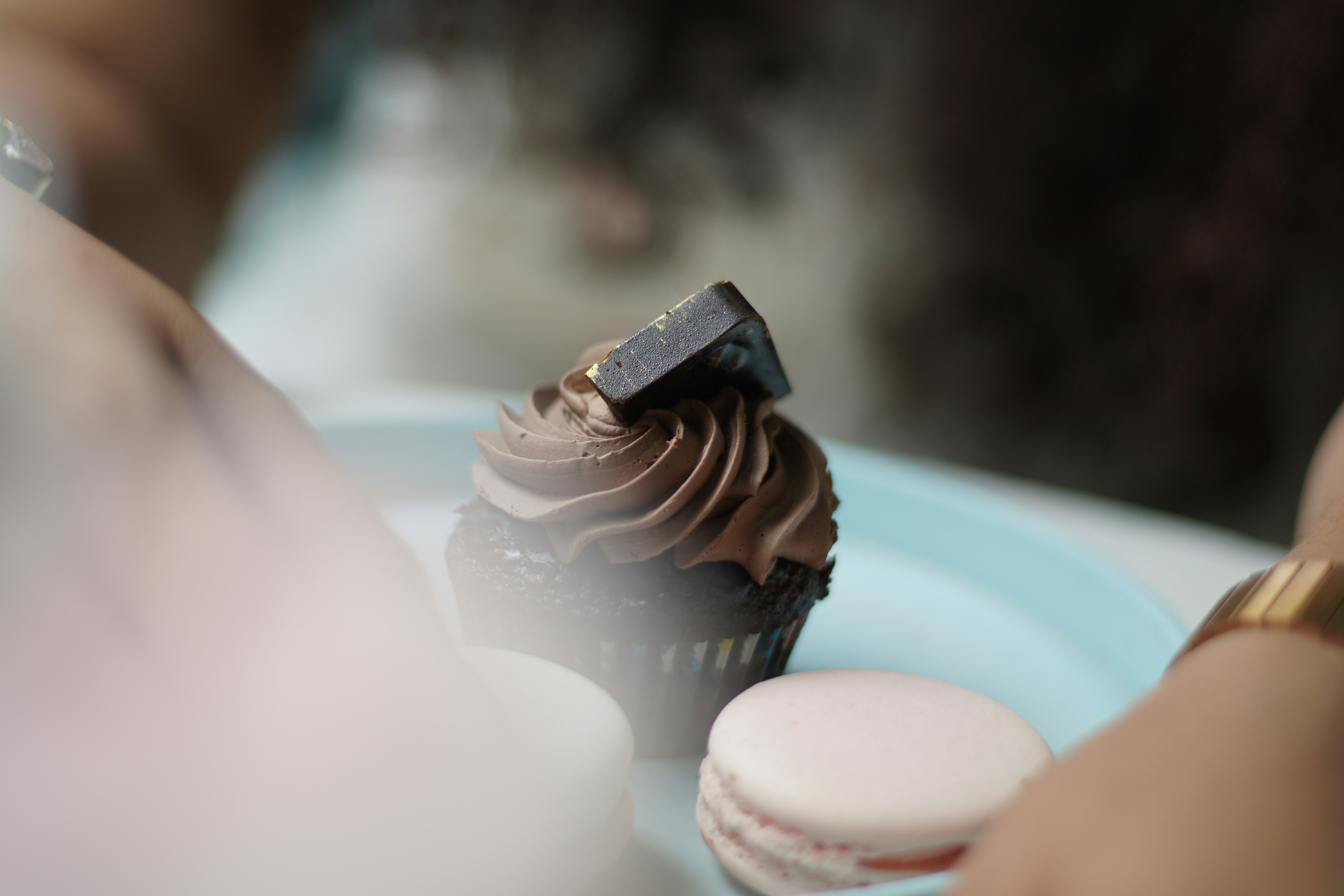 A close up of a person holding a plate with a cupcake on it