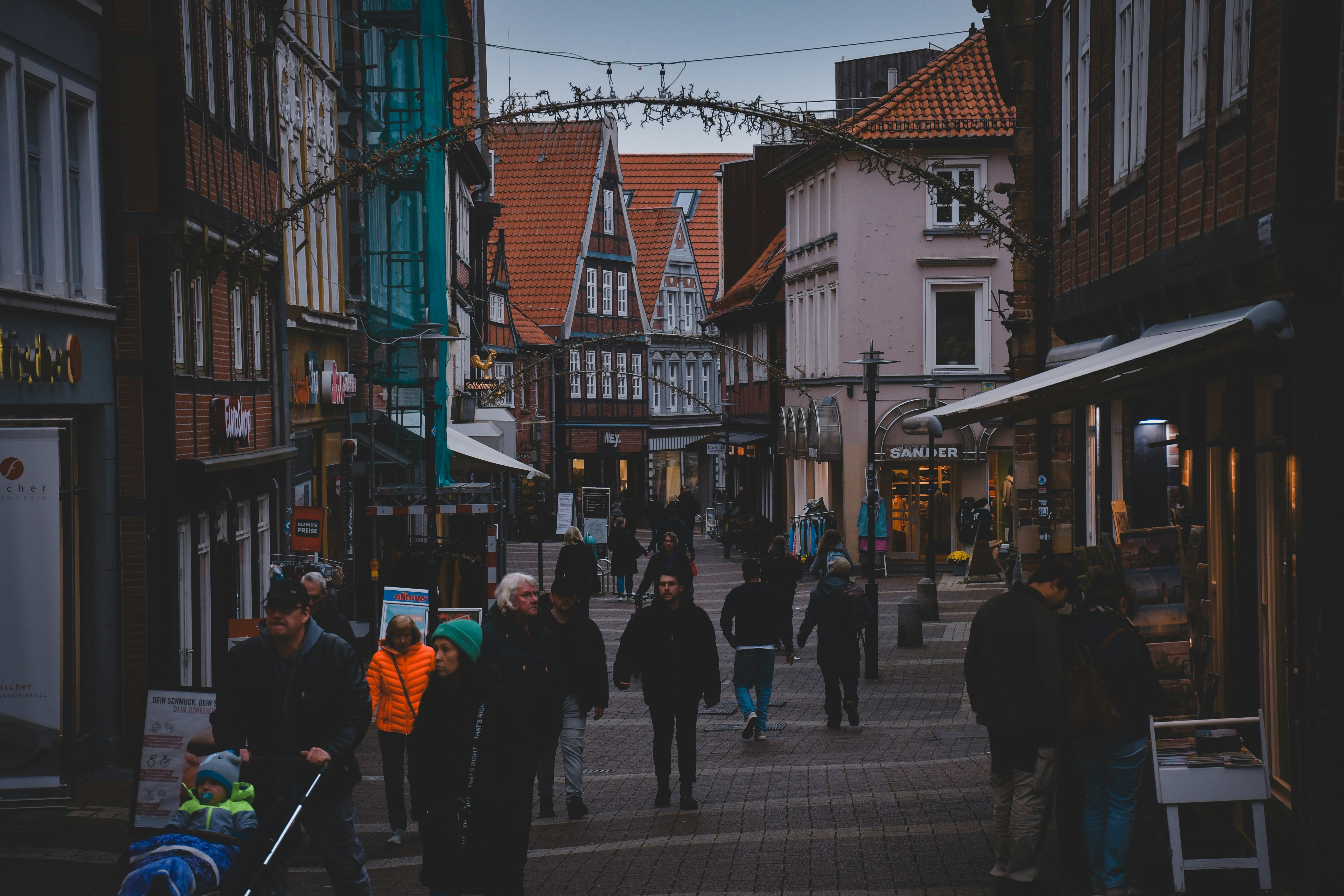 A group of people walking down a street next to tall buildings
