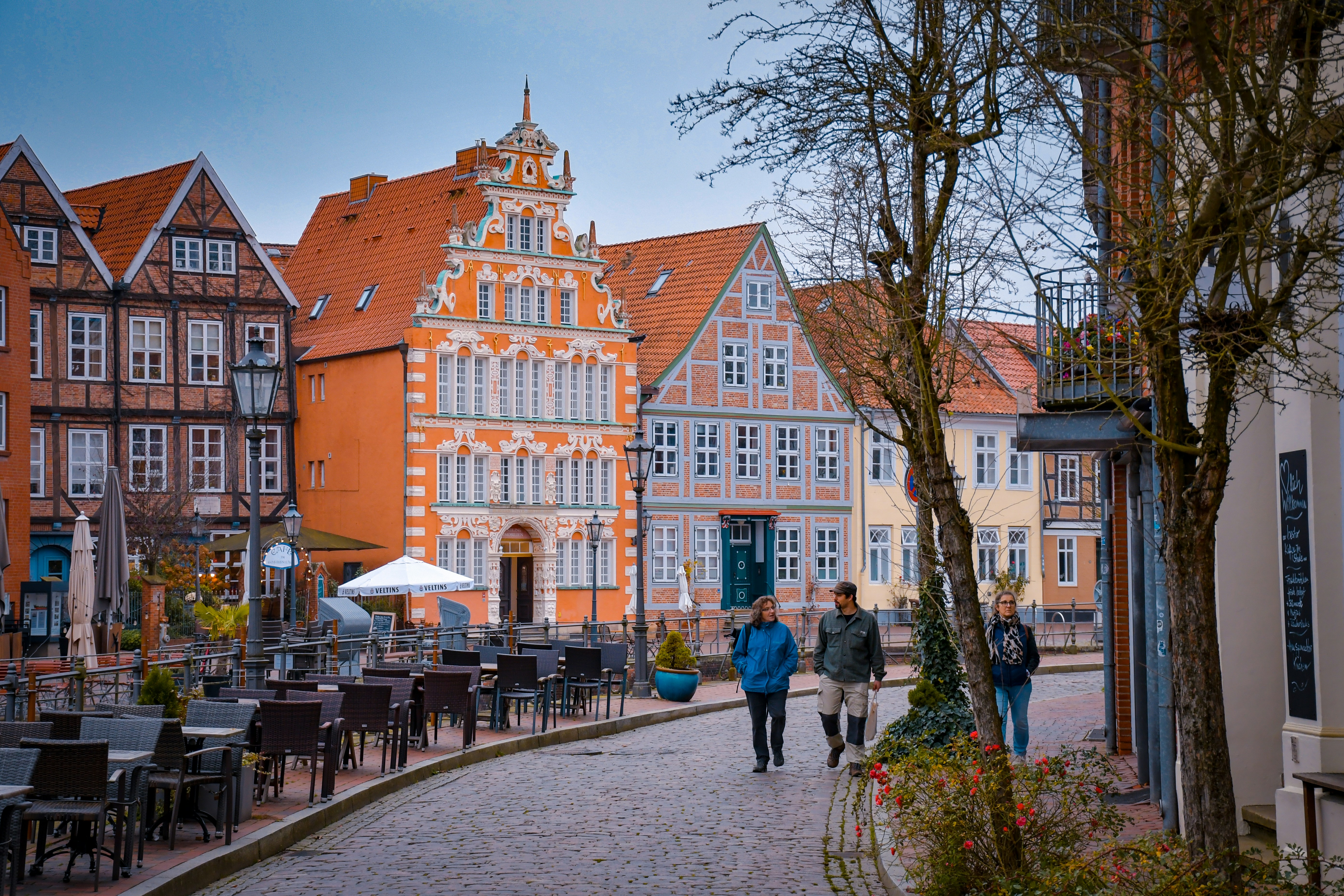 A group of people walking down a street next to tall buildings
