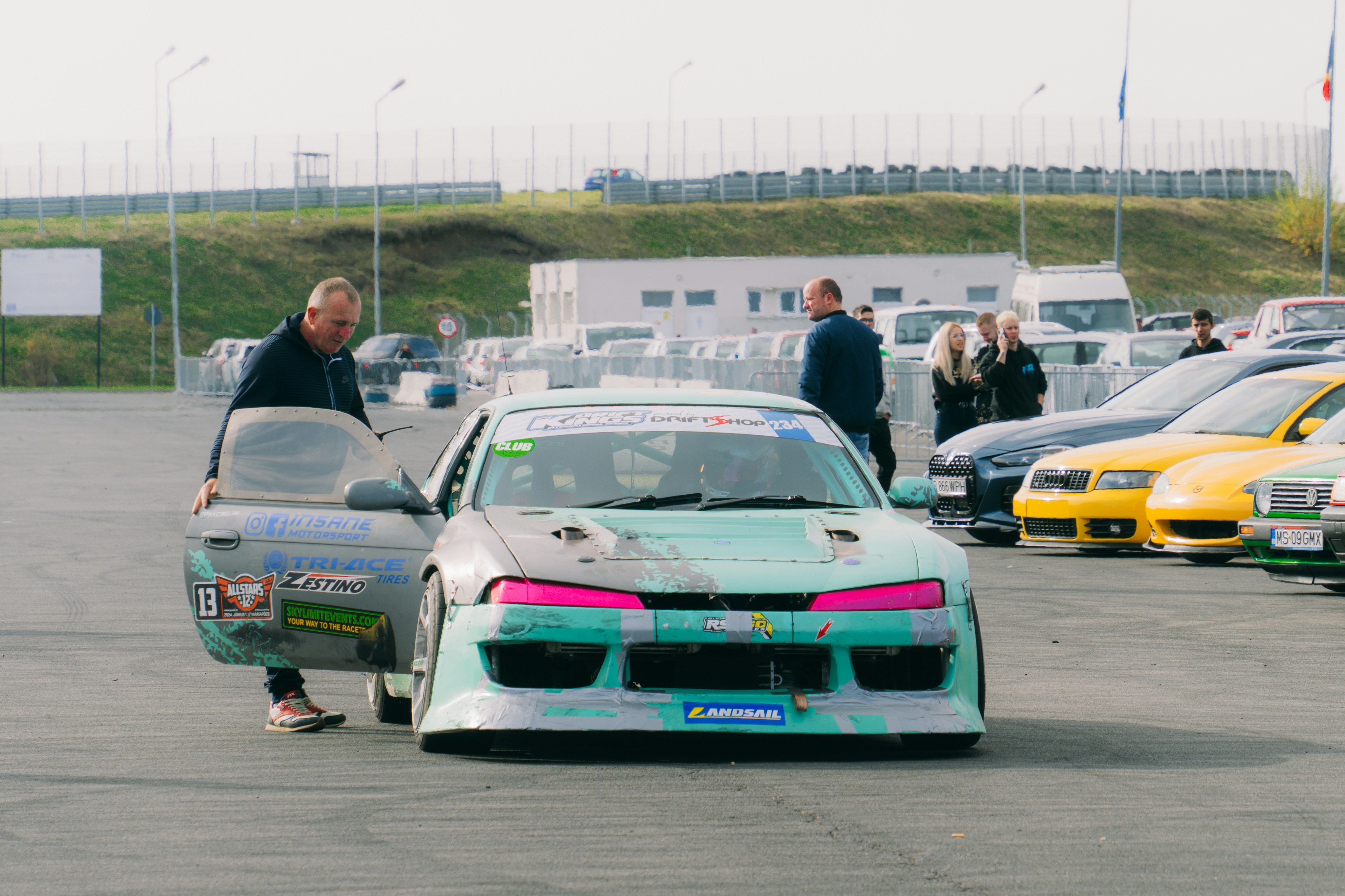 A man standing next to a car in a parking lot