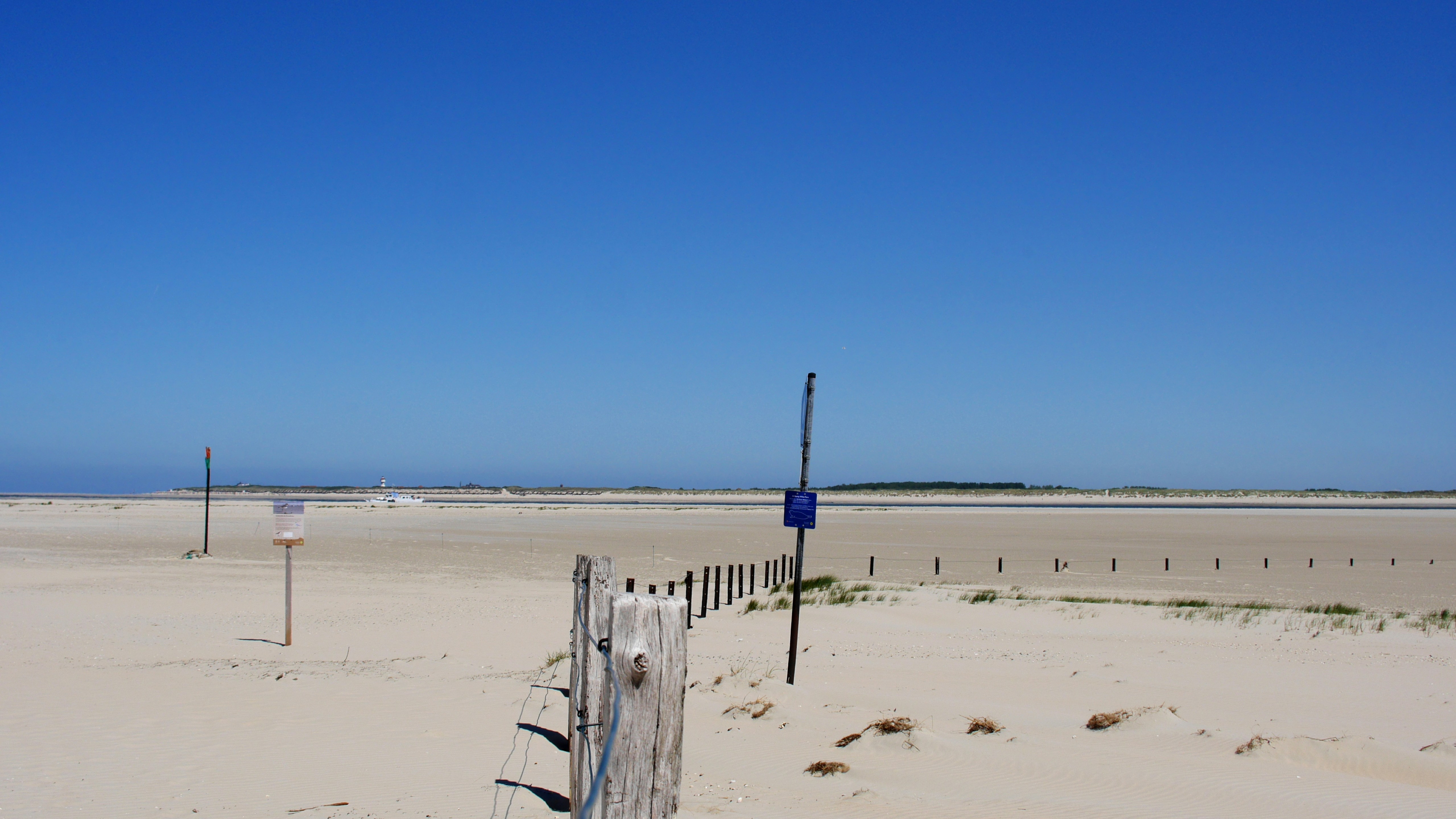 A fence on a beach with a blue sky in the background