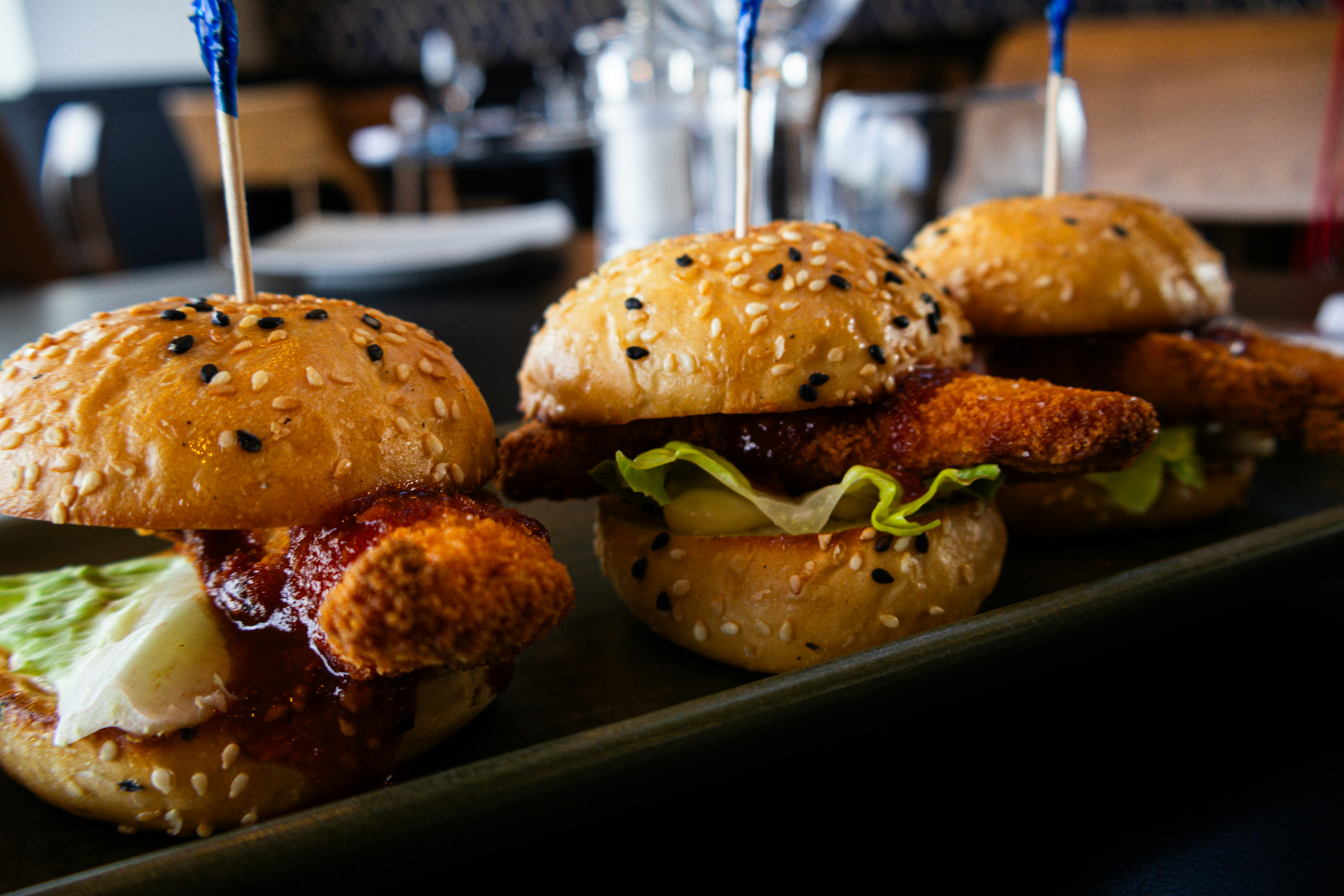 A black tray topped with mini sandwiches on top of a table