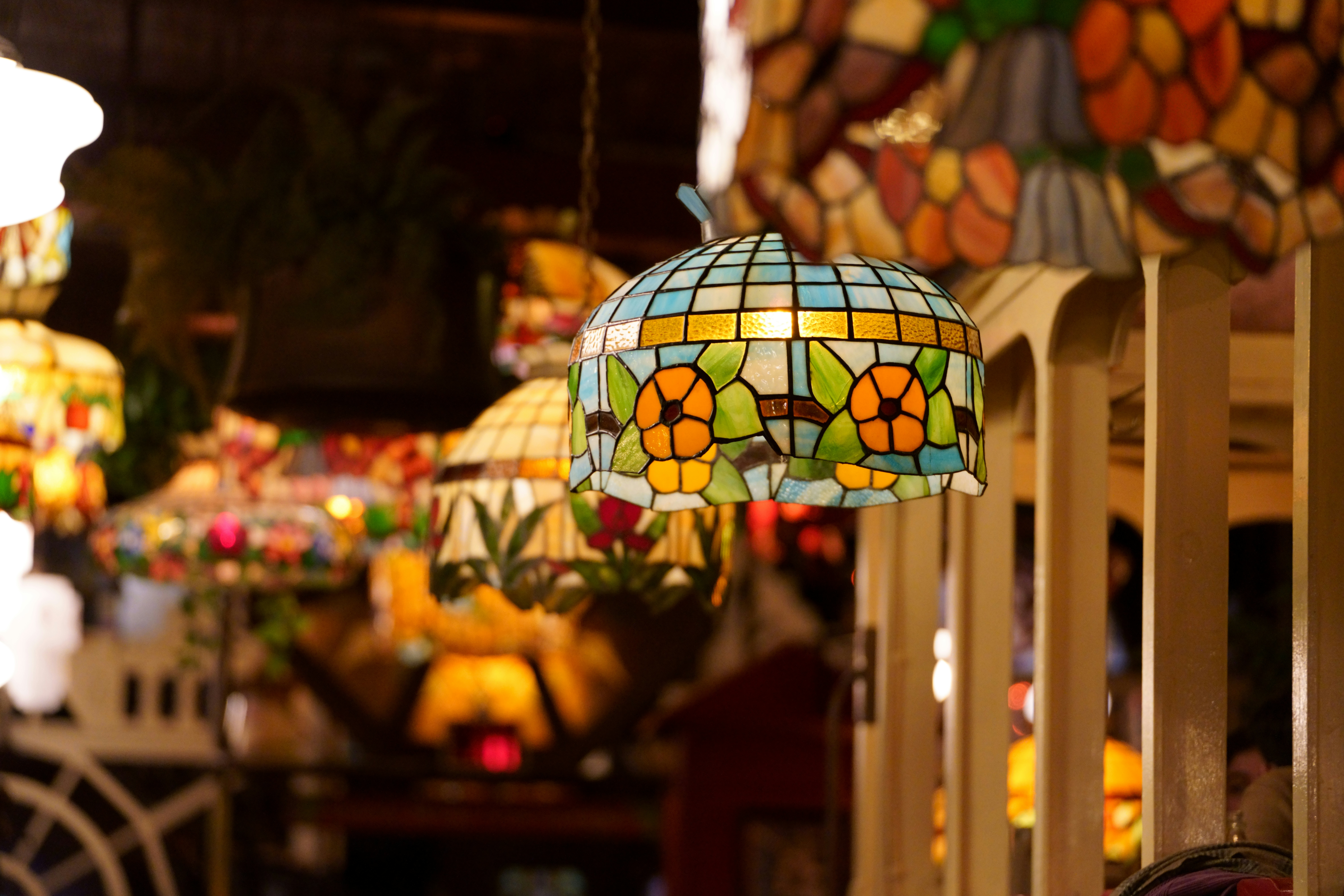 Colorful stained glass table lamp in Tiffany style, illuminated on dark background