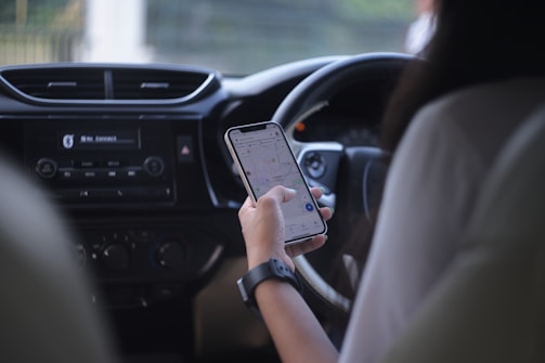 A woman holding a cell phone while driving a car