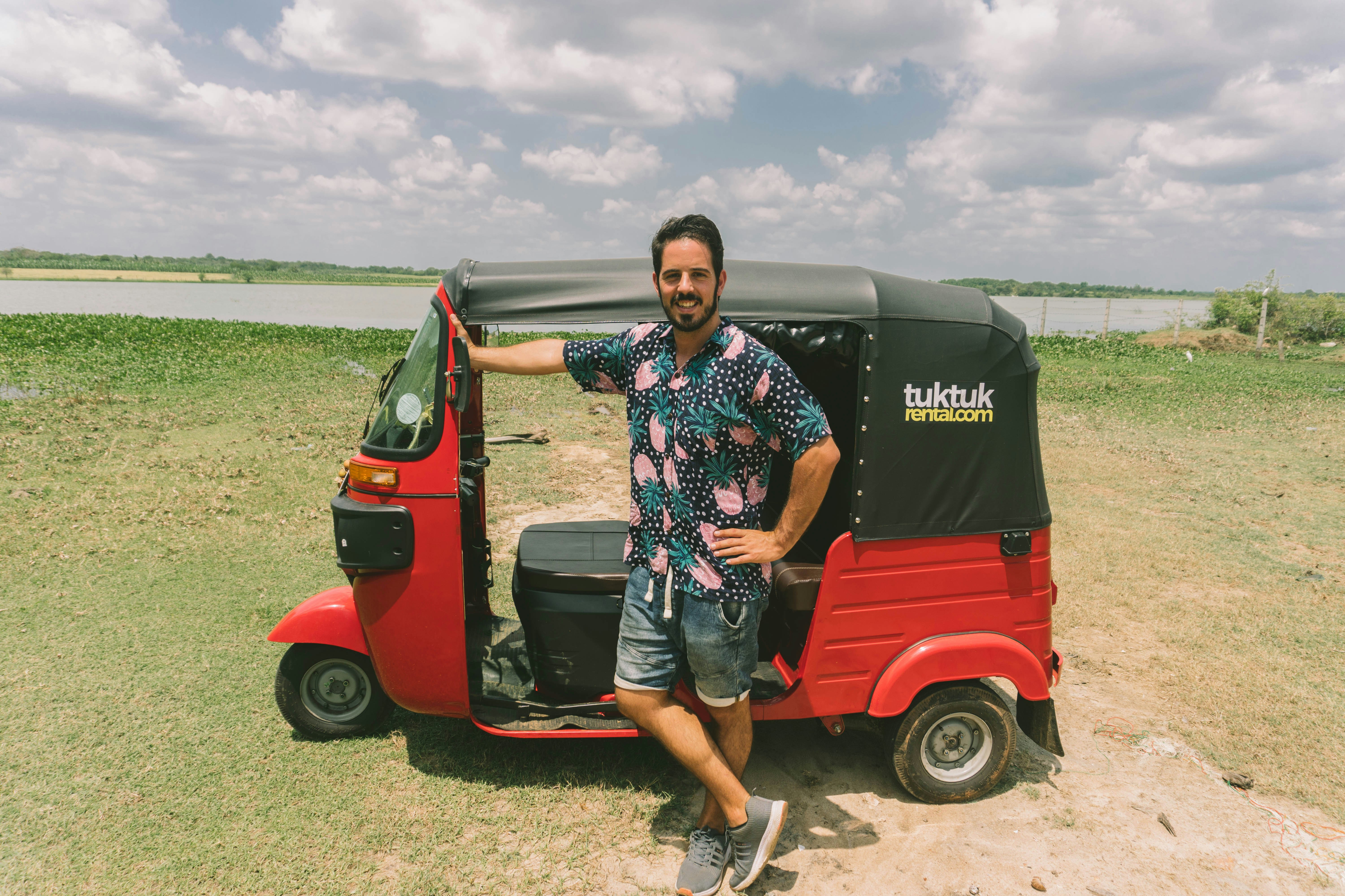 A man standing next to a red and black golf cart