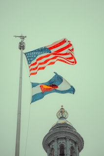 Two american and russian flags flying in front of a building