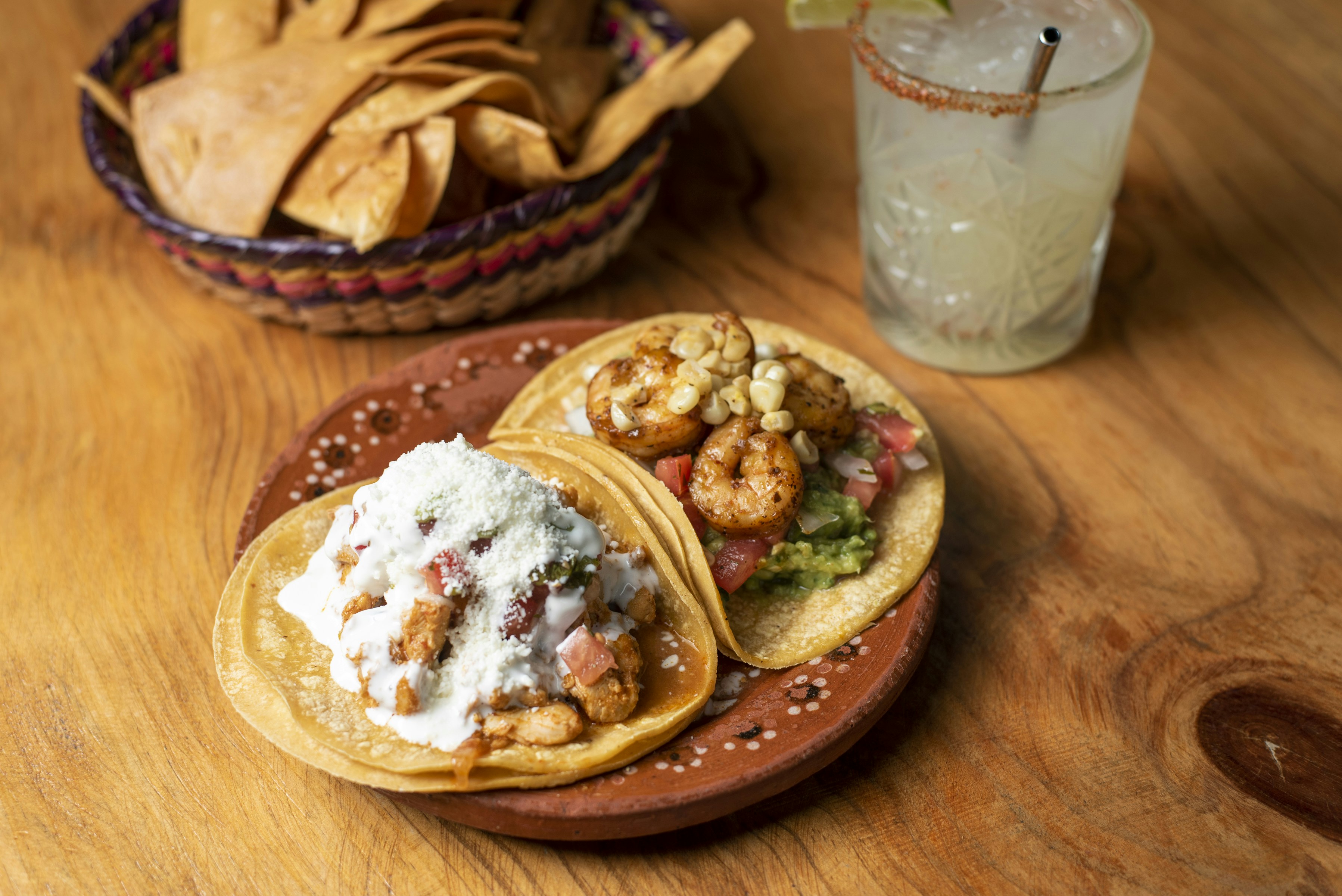 Un tavolo di legno sormontato da tre tacos e una bevanda