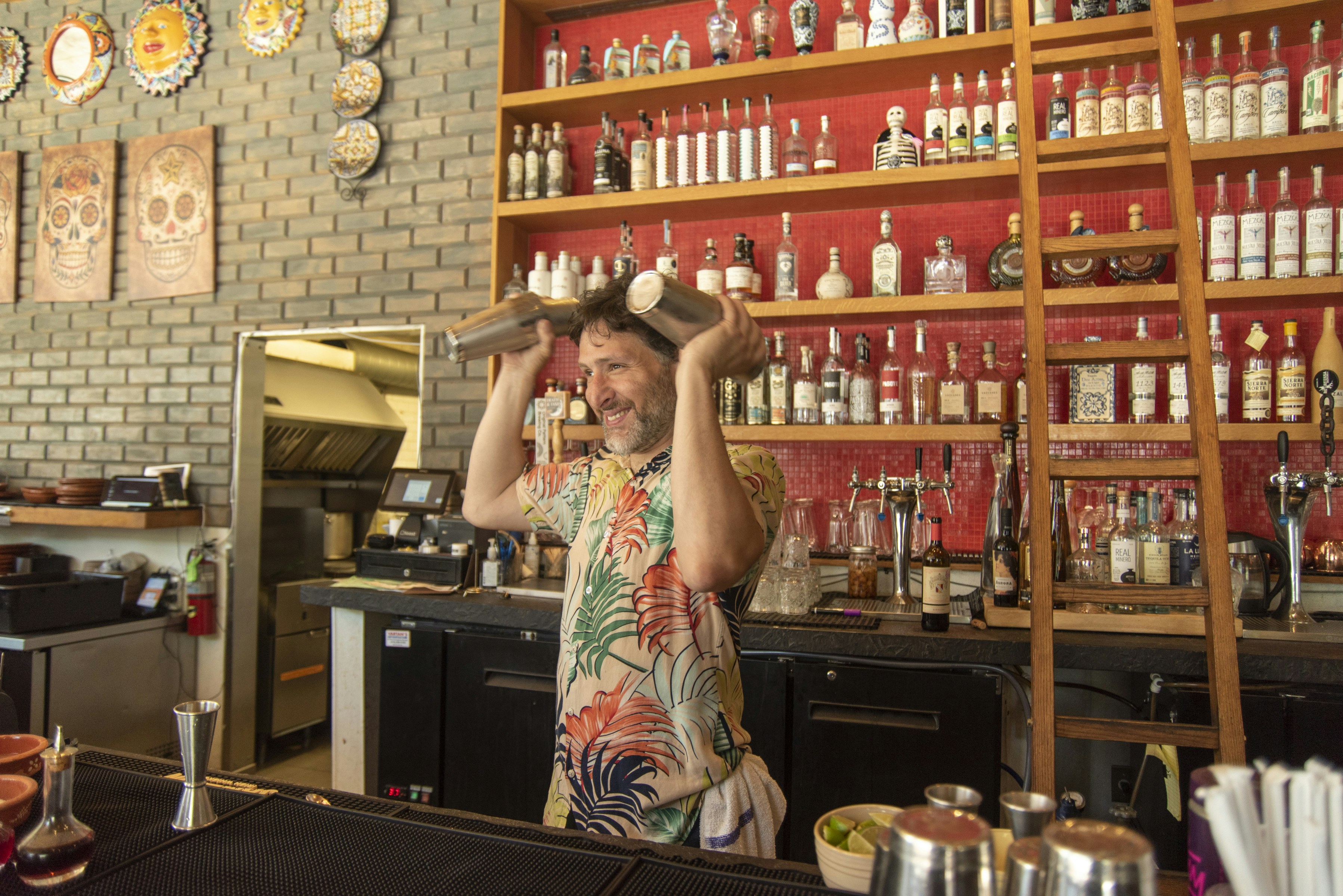 Bartender in front of red back-bar shelves