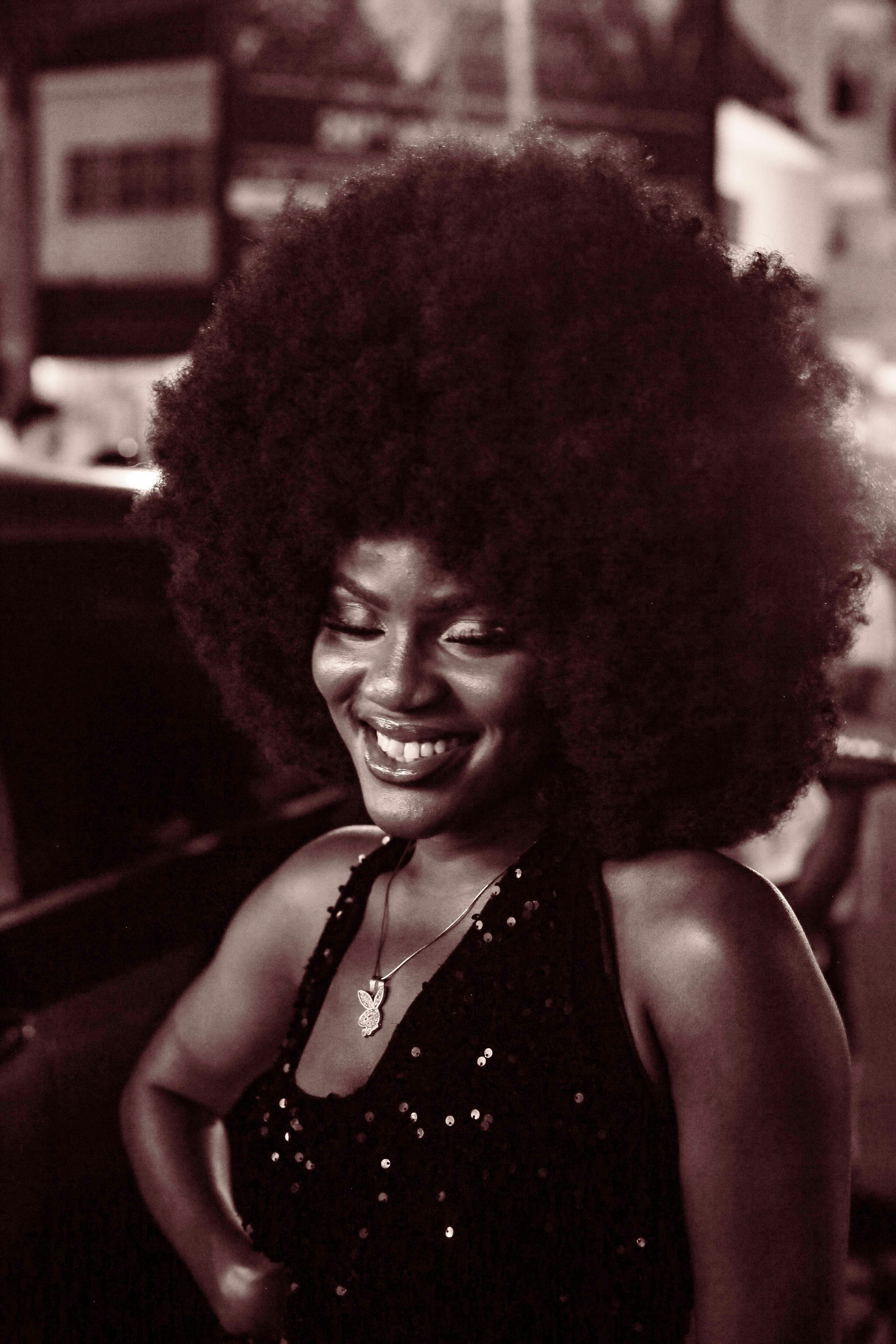 A woman with an afro standing next to a car