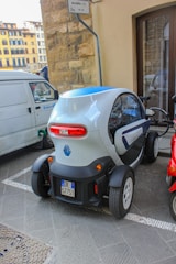 A person on a scooter next to a small car