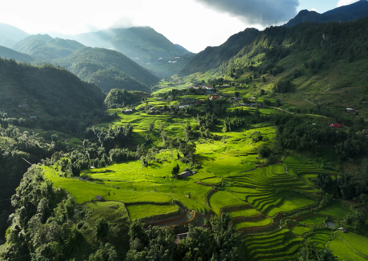 A green valley of rice terraces and villages near Sa Pa, with mountains behind
