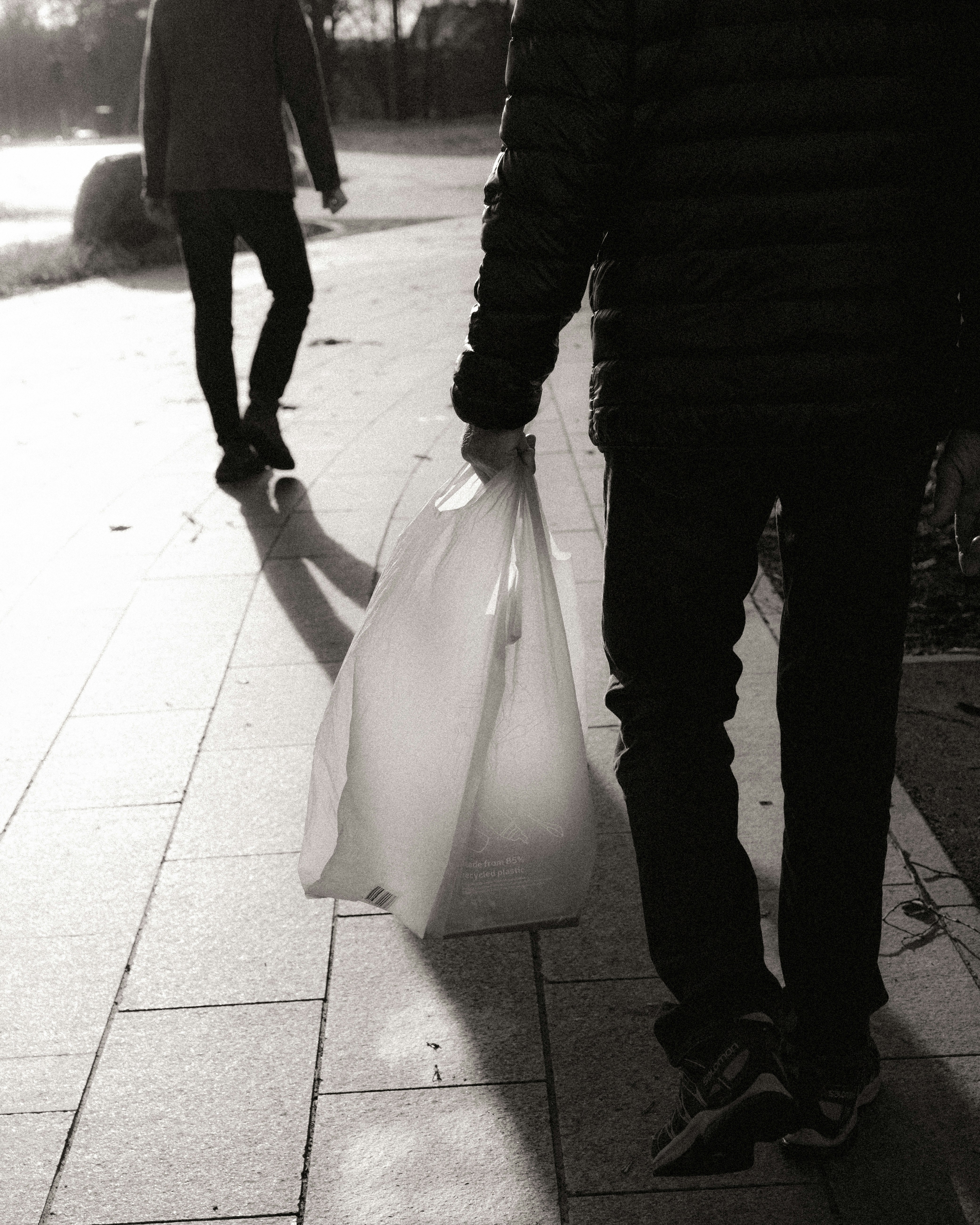 A man walking down a sidewalk carrying a bag