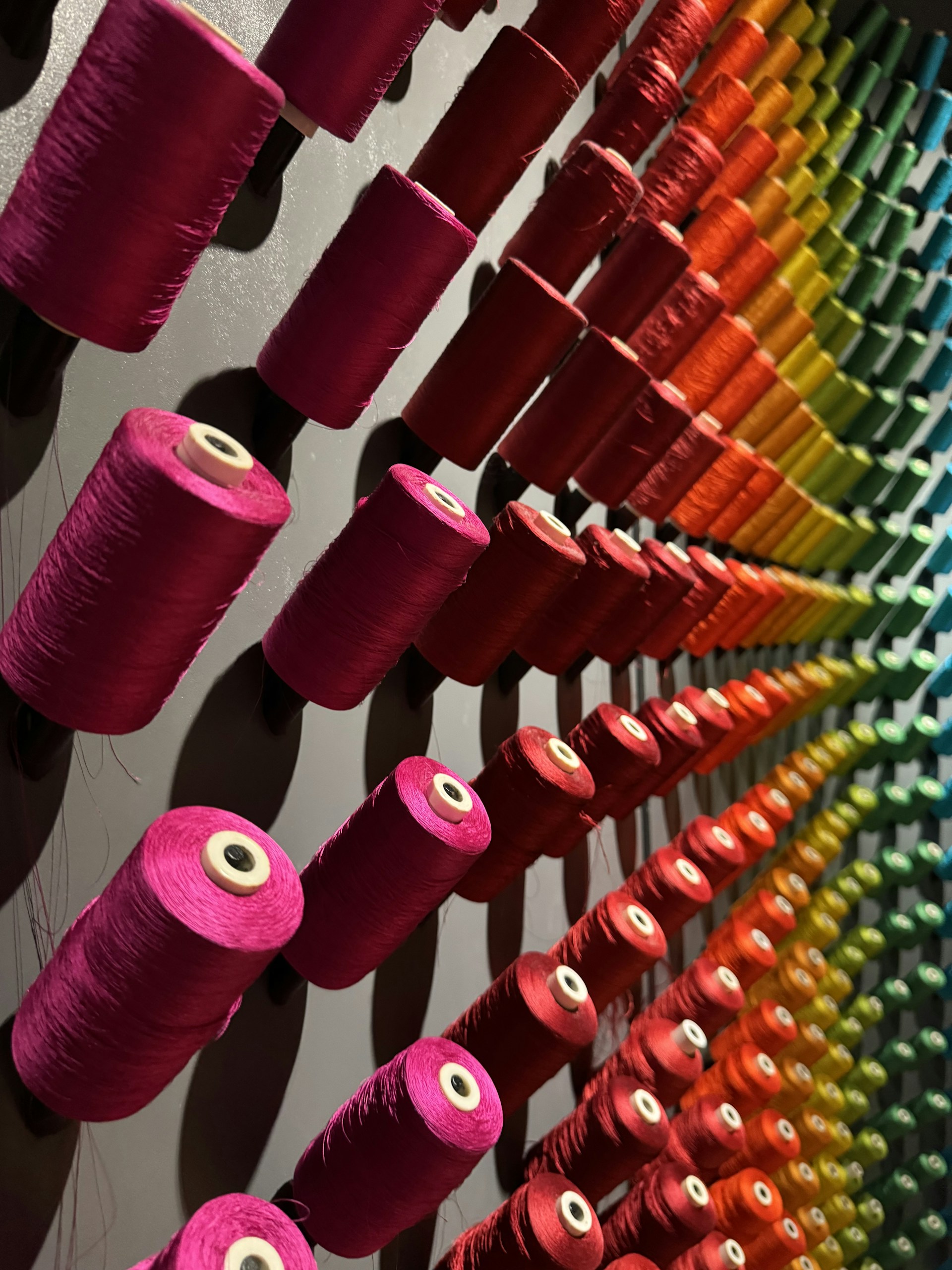 Many spools of thread are lined up on a wall