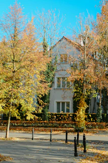 A large white house surrounded by trees in the fall