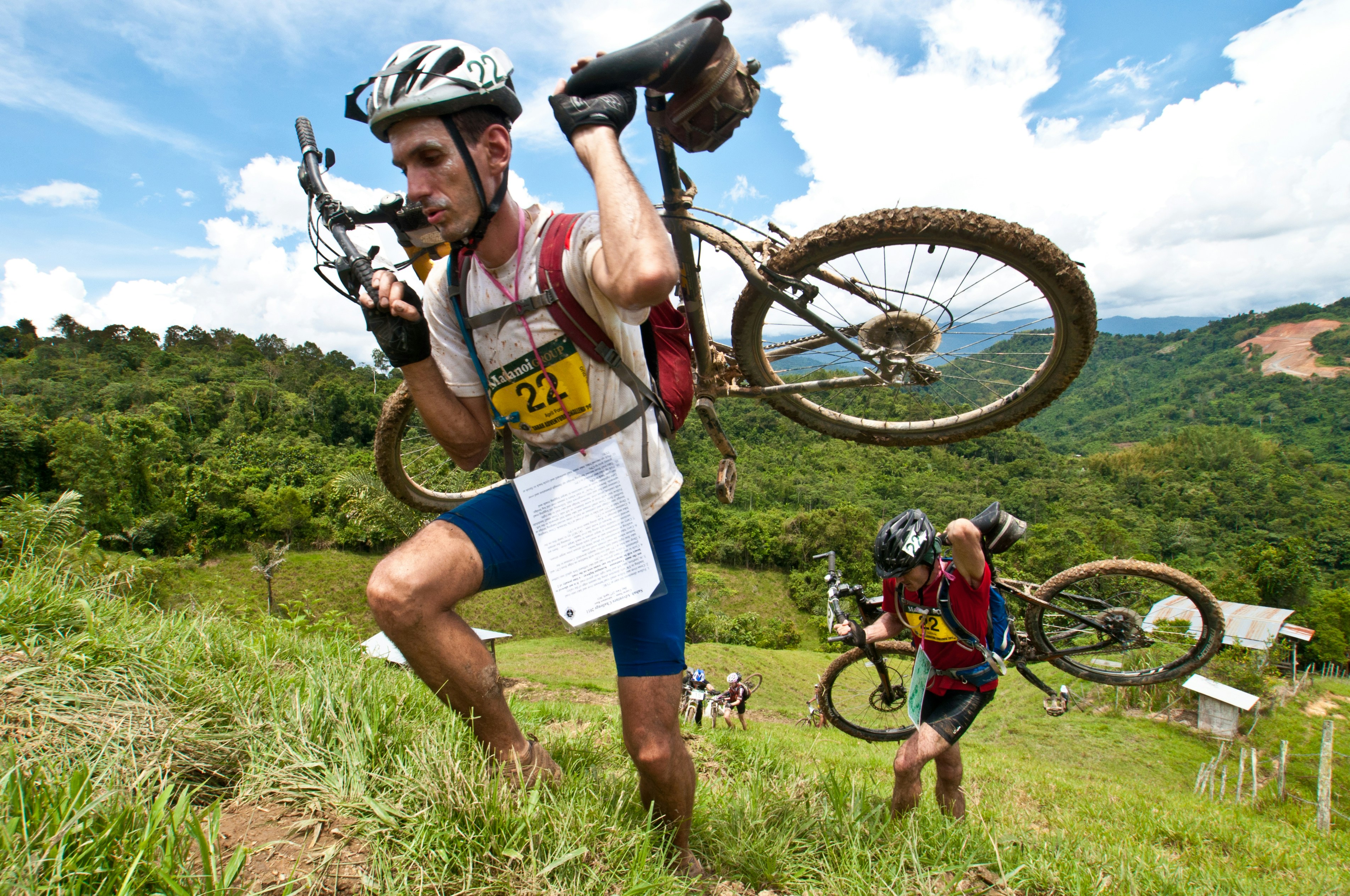 A man carrying a bike up a hill
