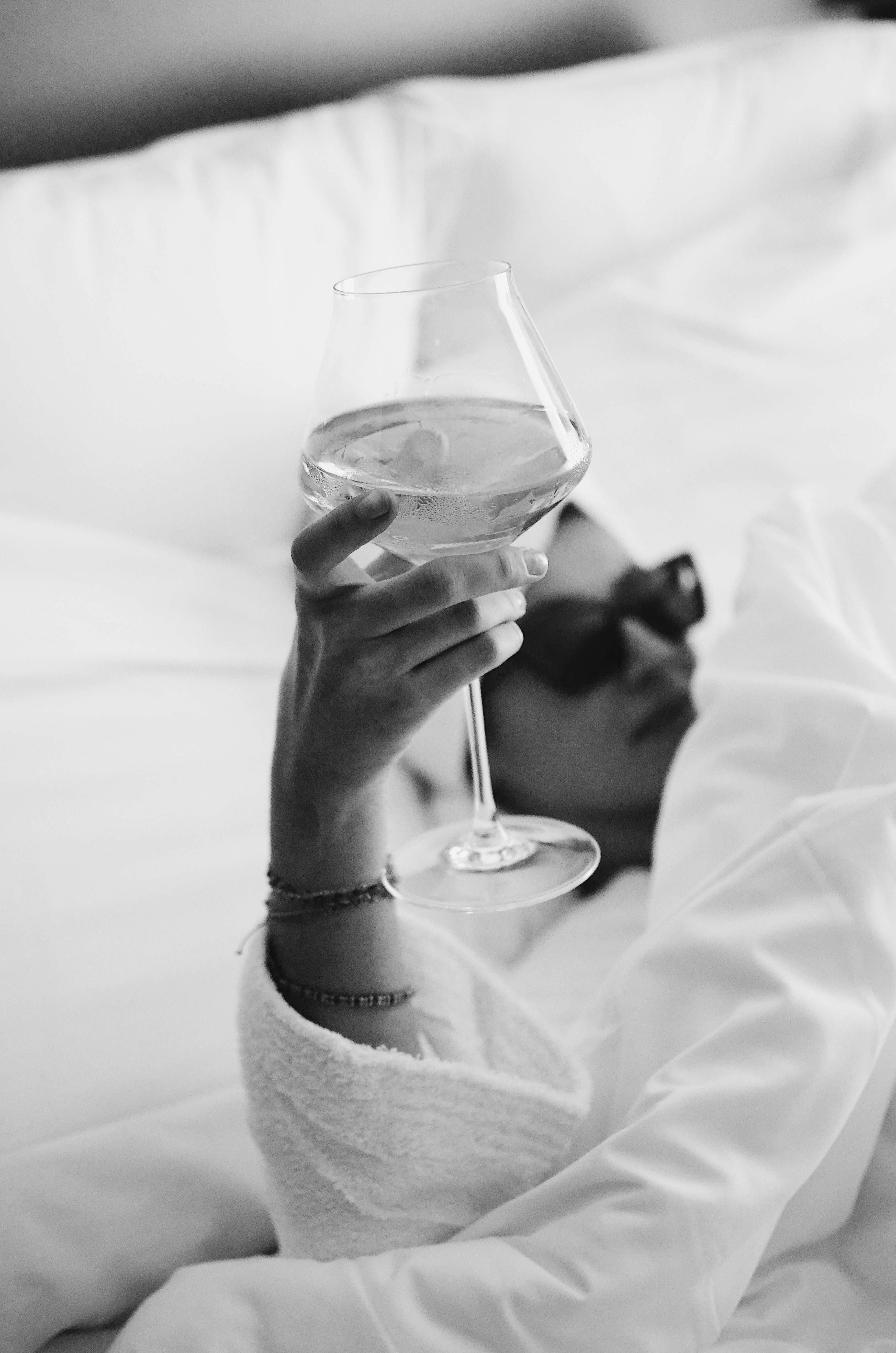 Eine Frau, die im Bett liegt und ein Glas Wein in der Hand hält