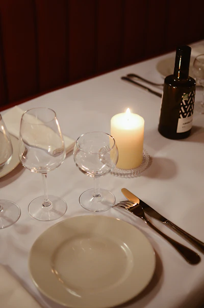 A table set for a formal fine-dining dinner with a lit candle