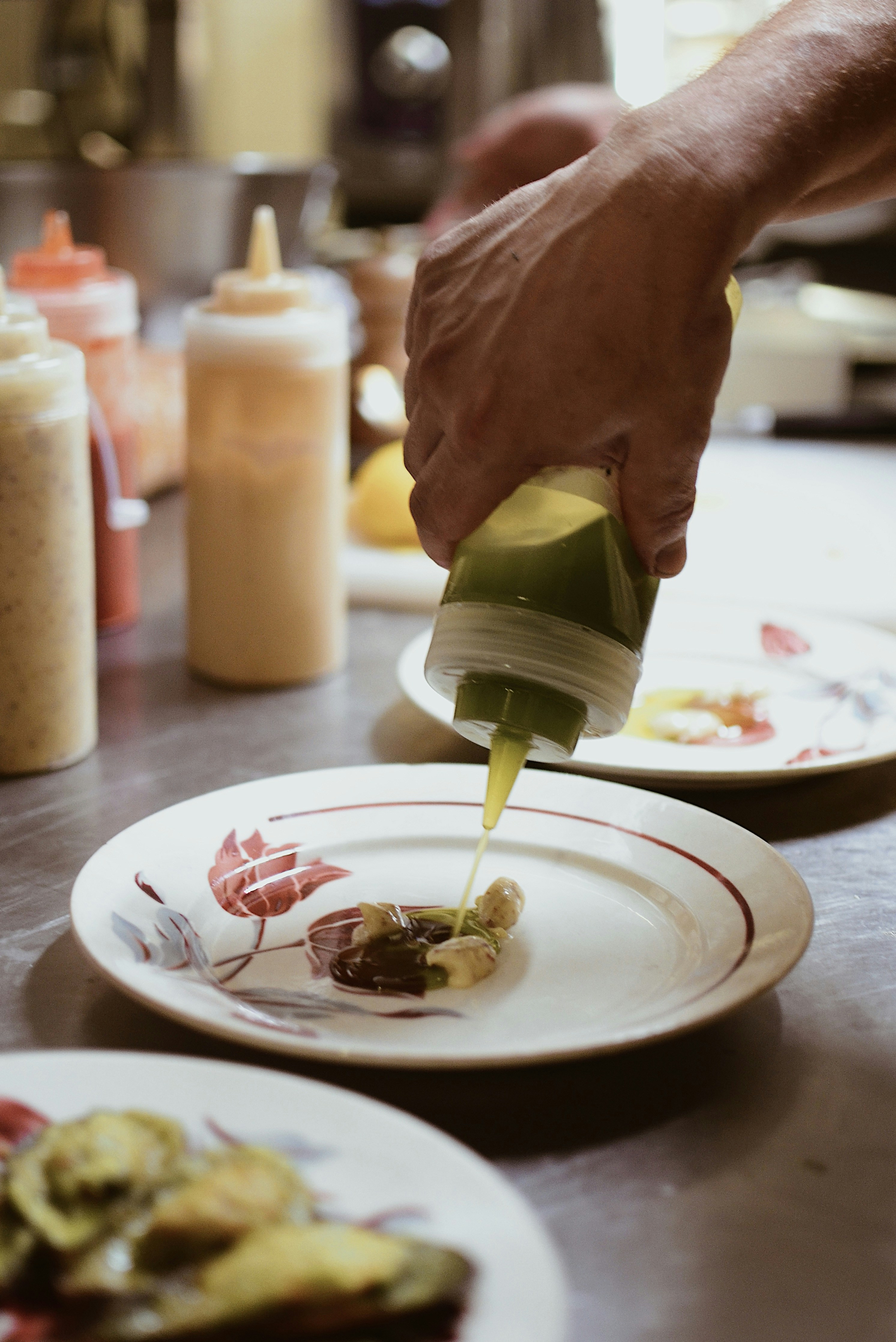 A person is pouring sauce on a plate