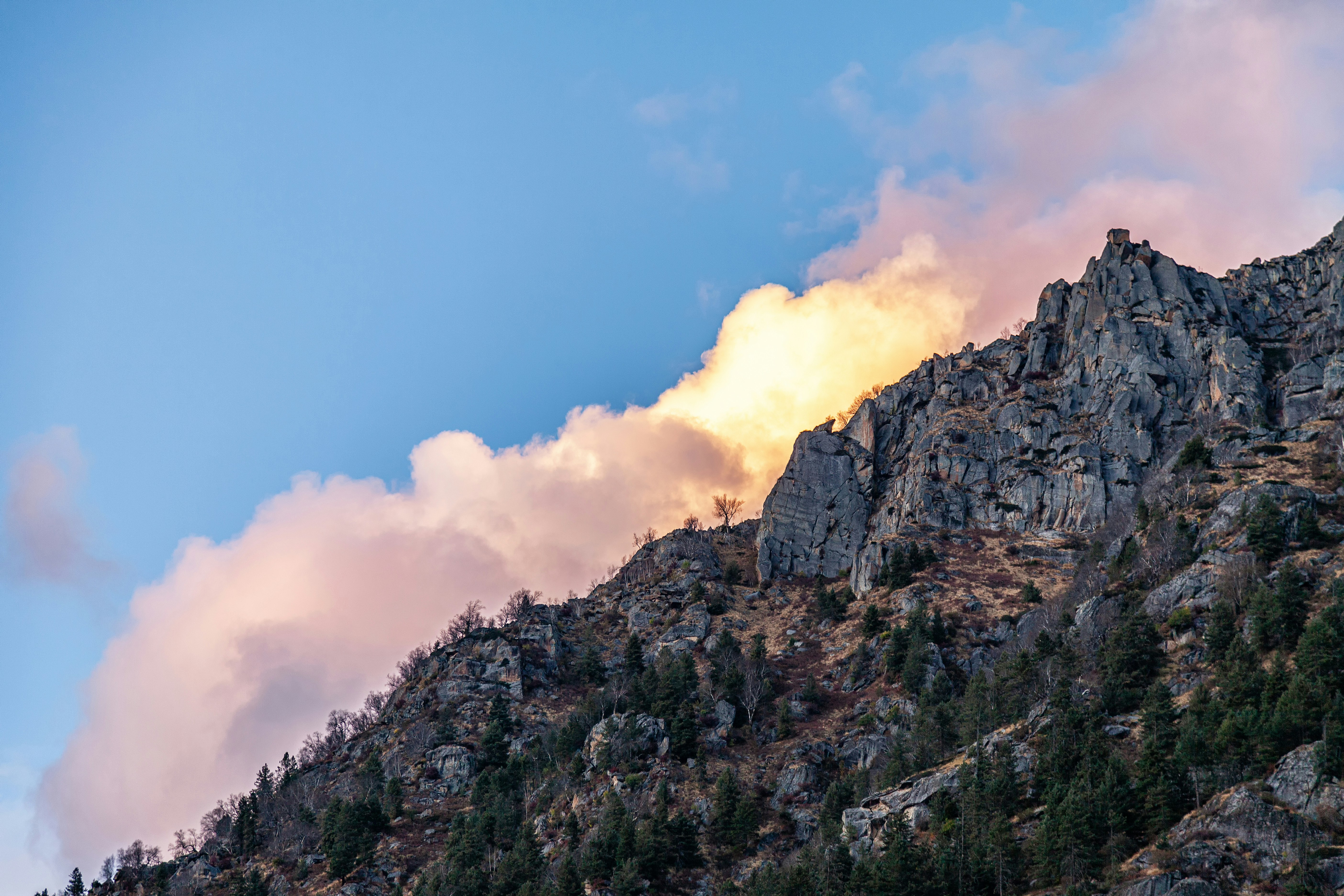 A very tall mountain with some clouds in the sky