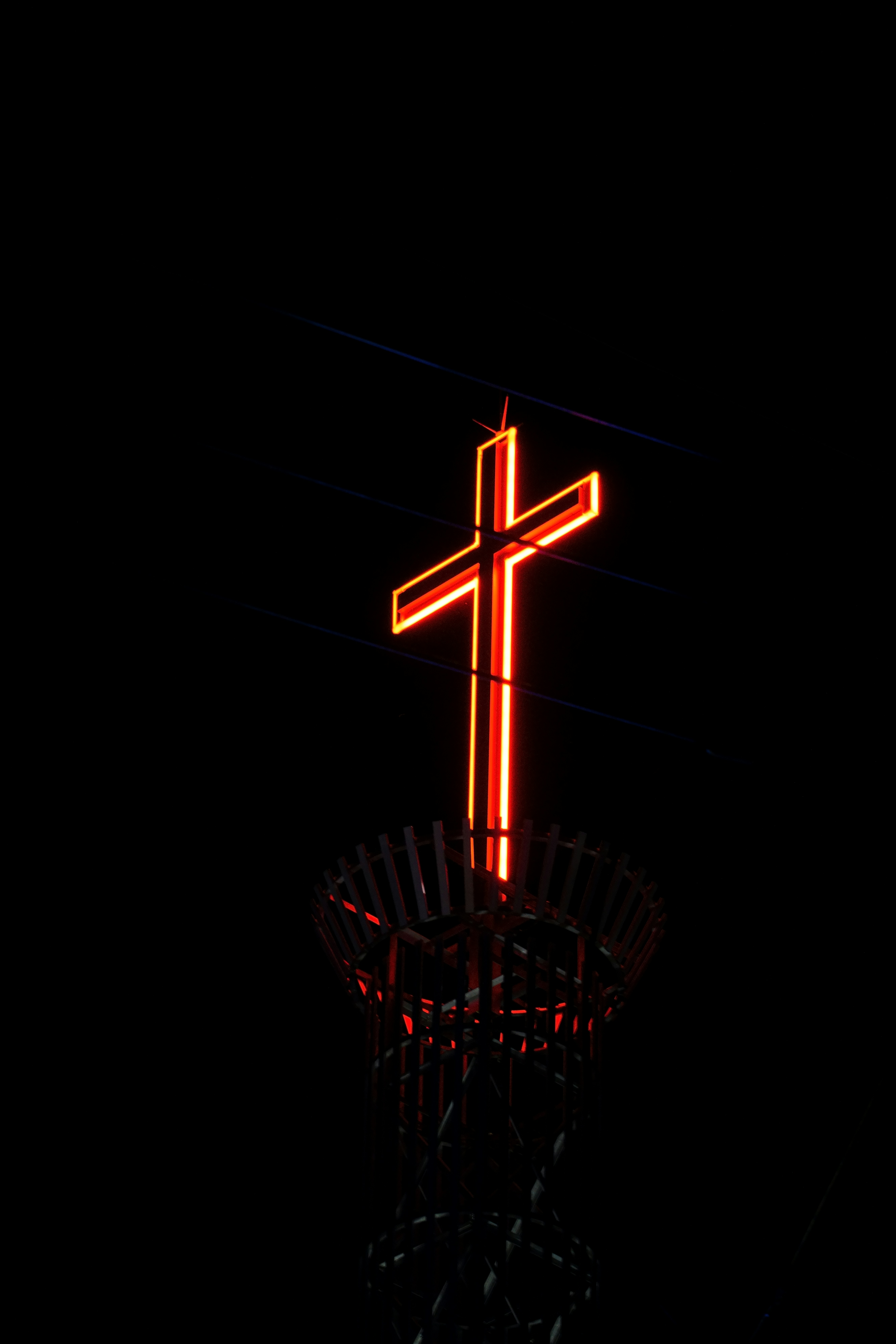 A cross on top of a tower lit up in the dark