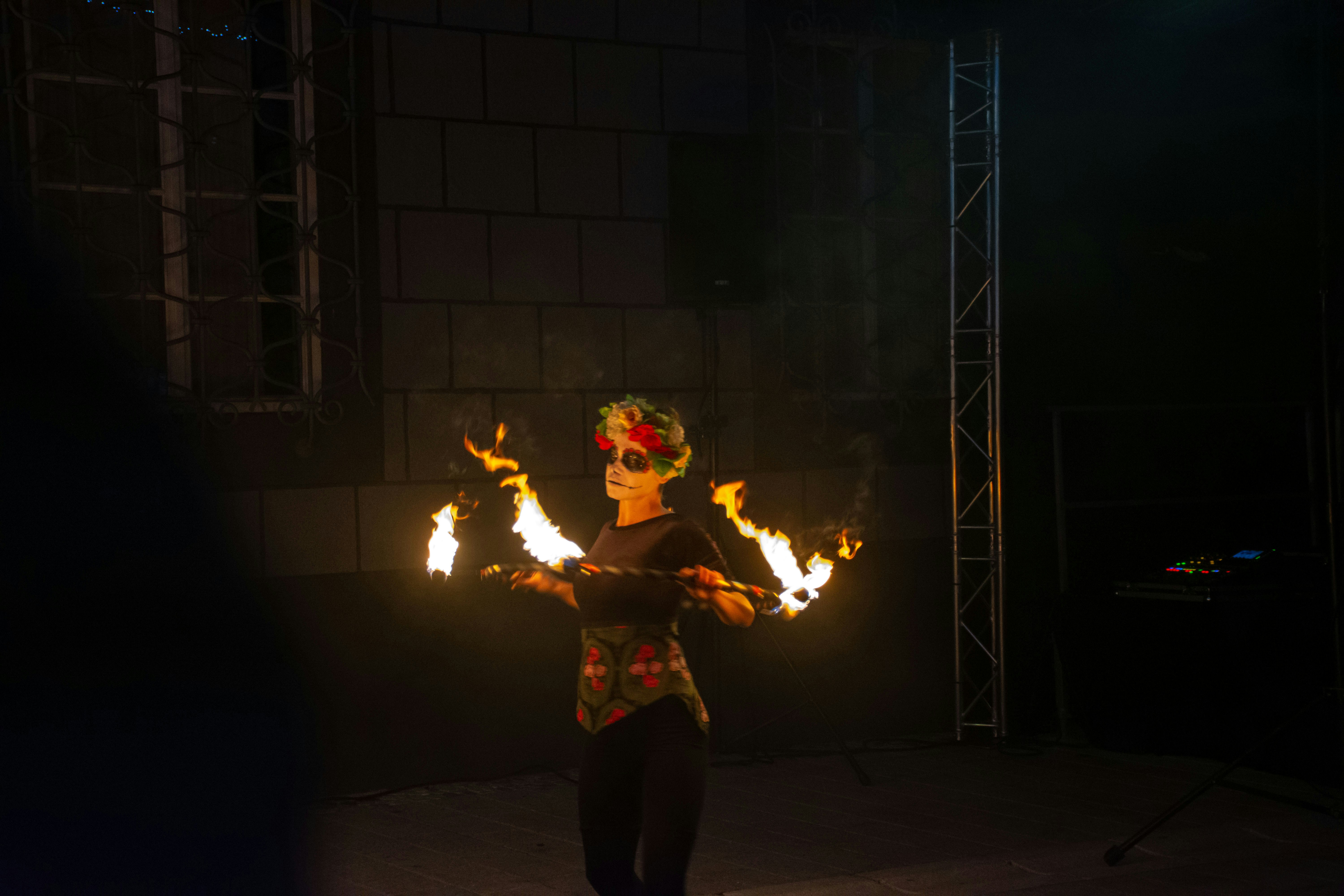 A woman is performing a fire show in the dark