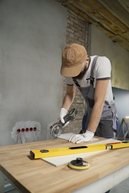 A man sanding a wooden table with a sander