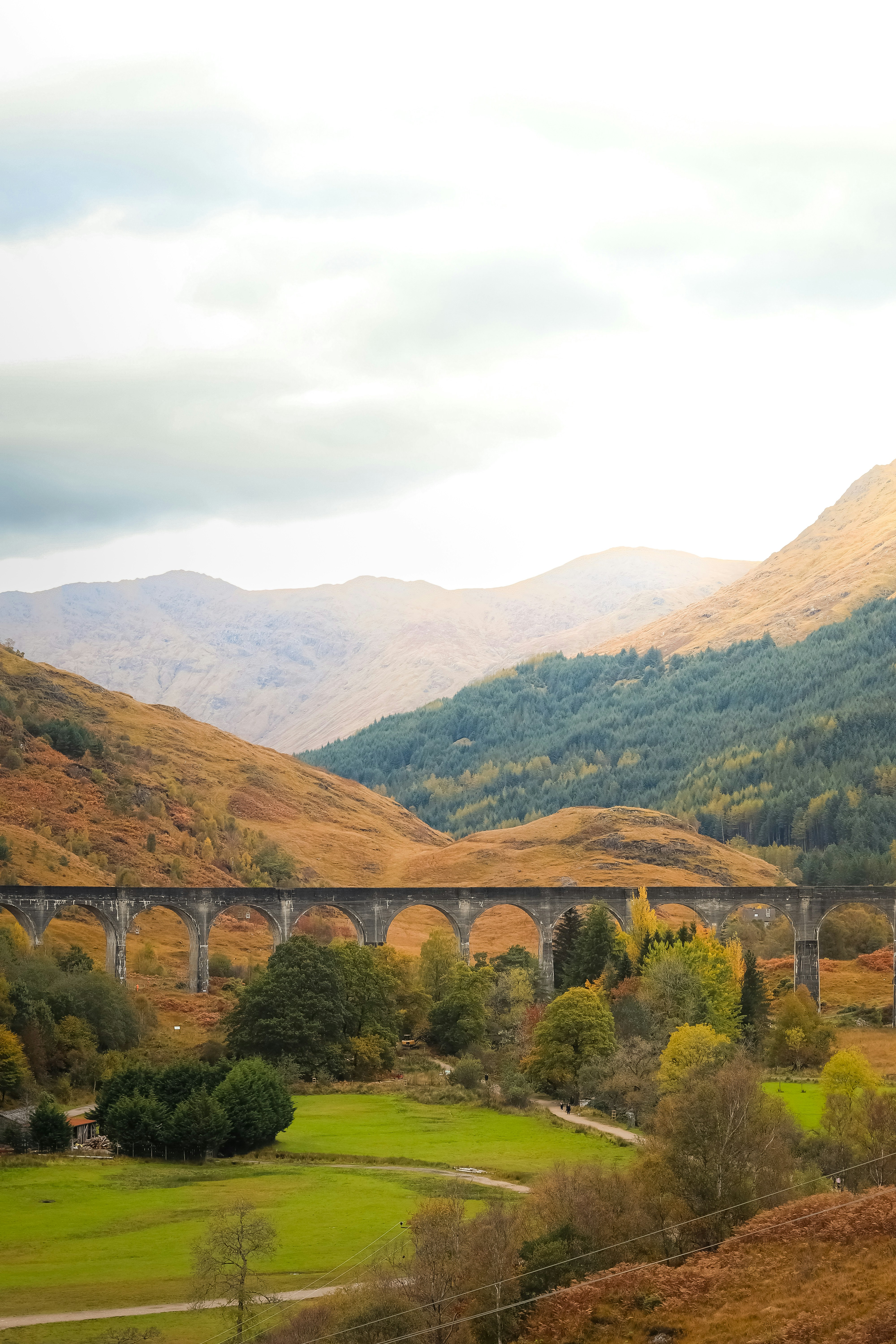 Panoramic train on stone viaduct in autumn mountain landscape