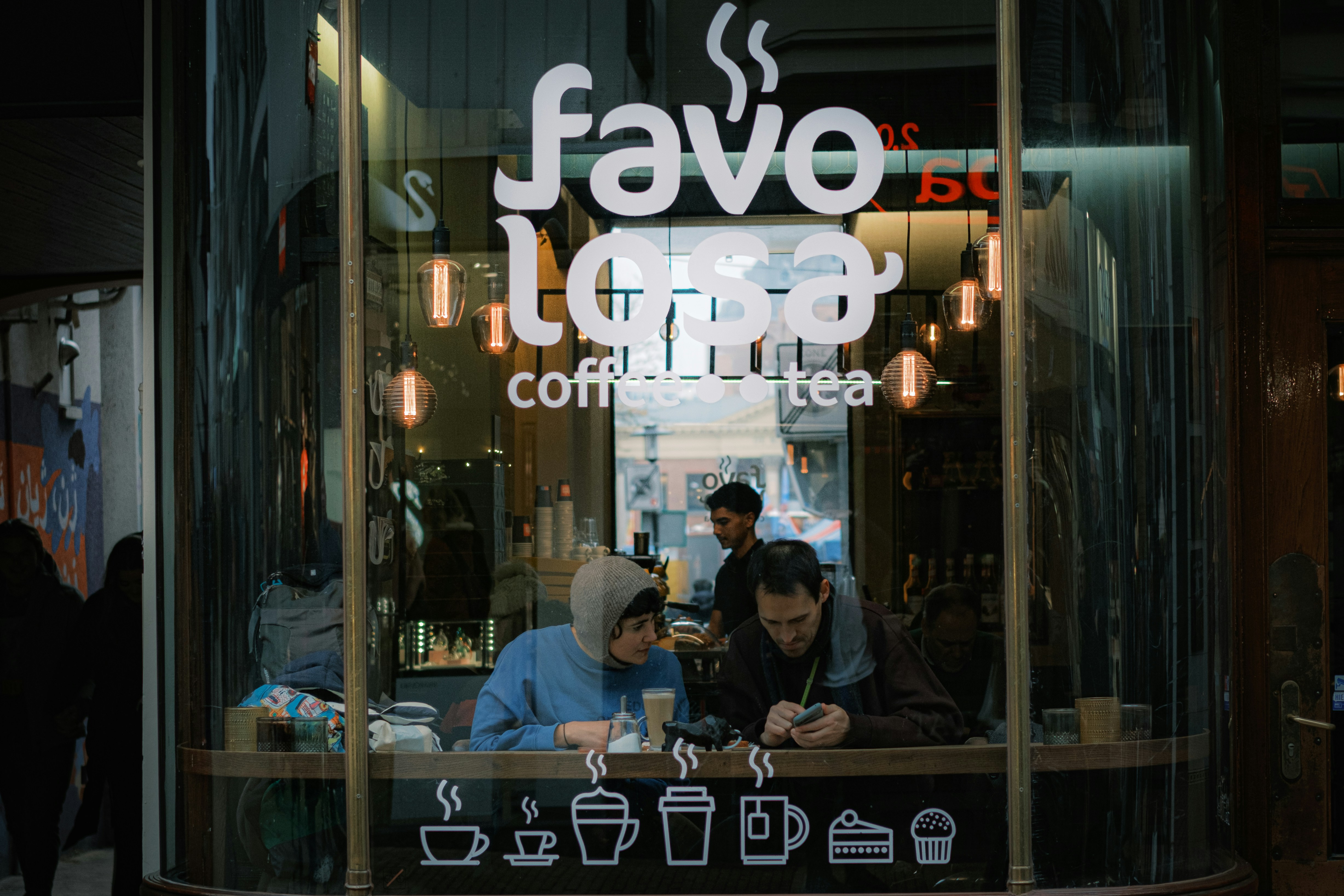 A couple of people sitting at a table in front of a restaurant