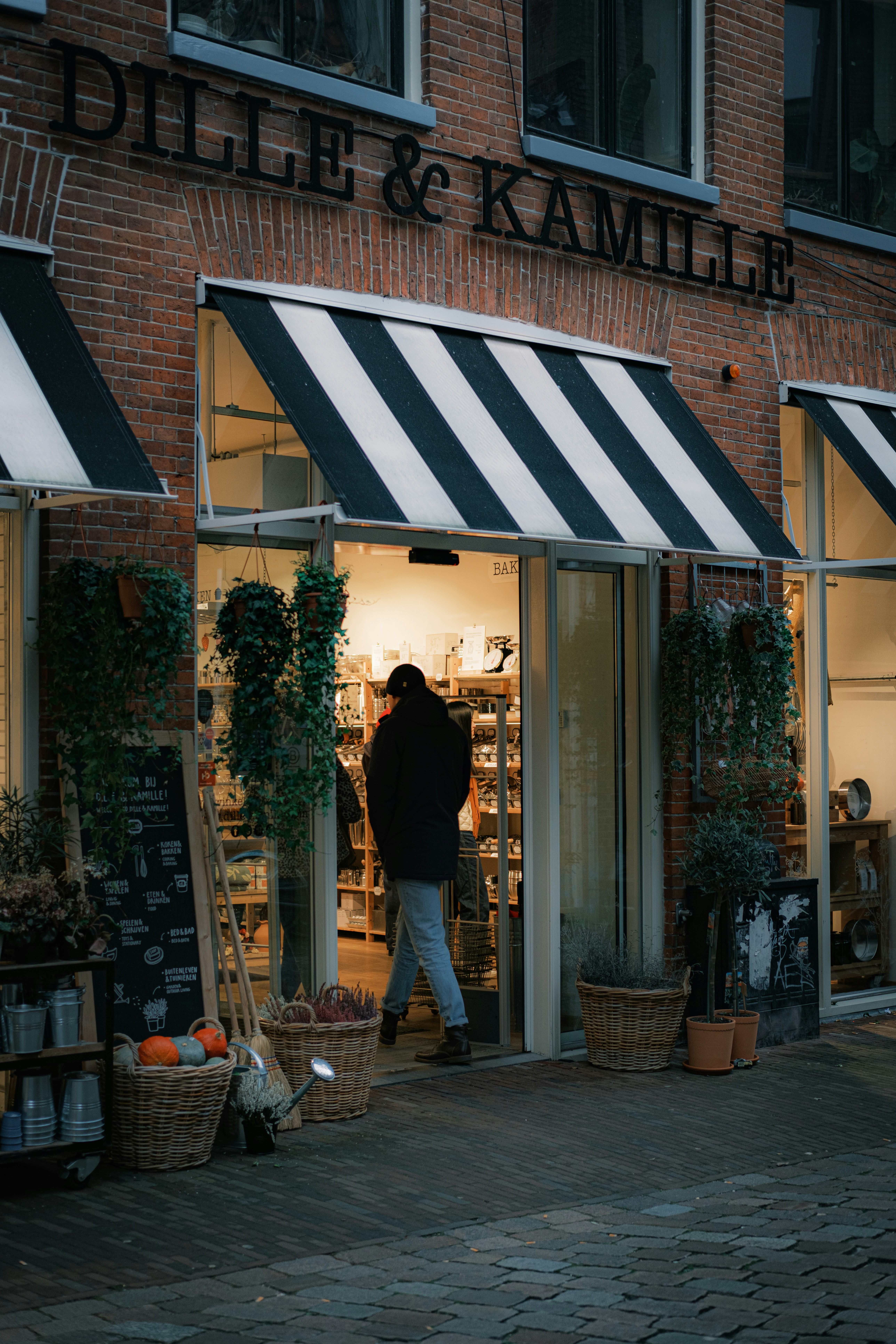 A person walking out of a store with a black and white awning