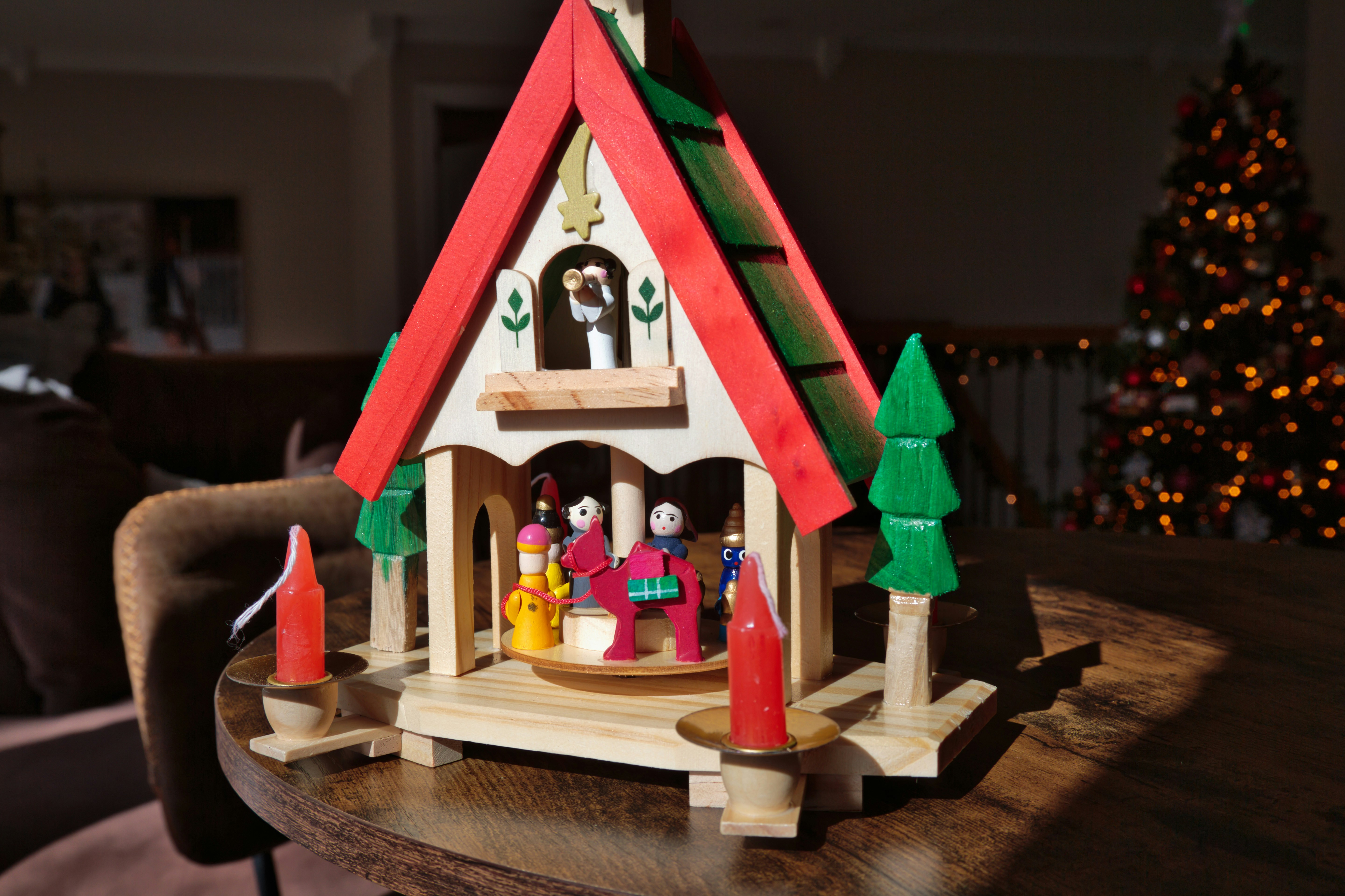 Una pequeña casa de madera con un árbol de Navidad al fondo