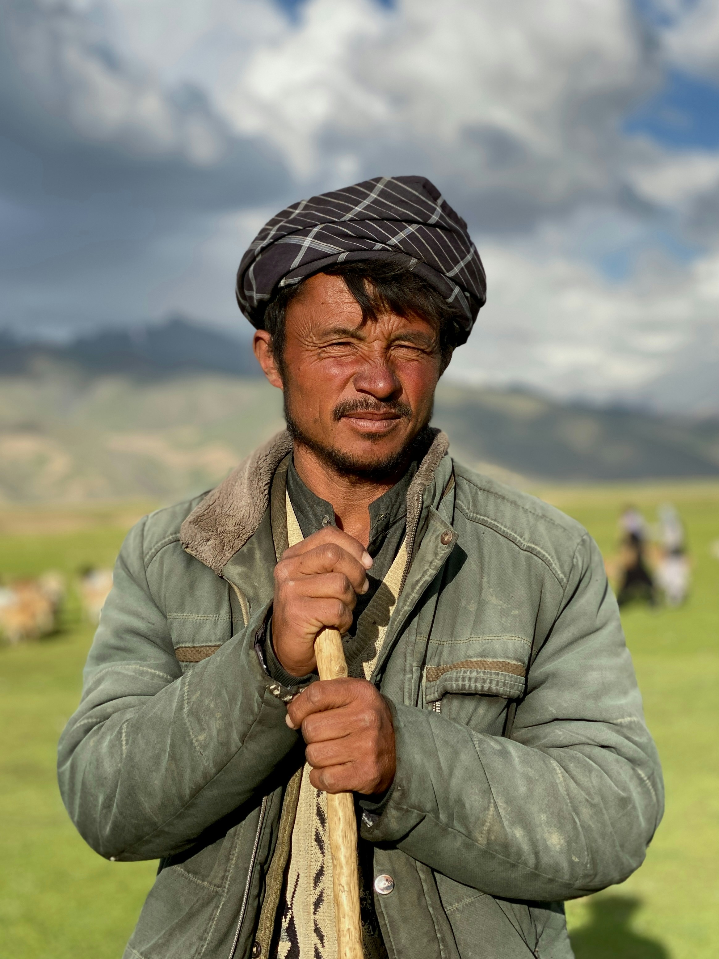 Ein Mann, der auf einem Feld steht und einen Stock hält