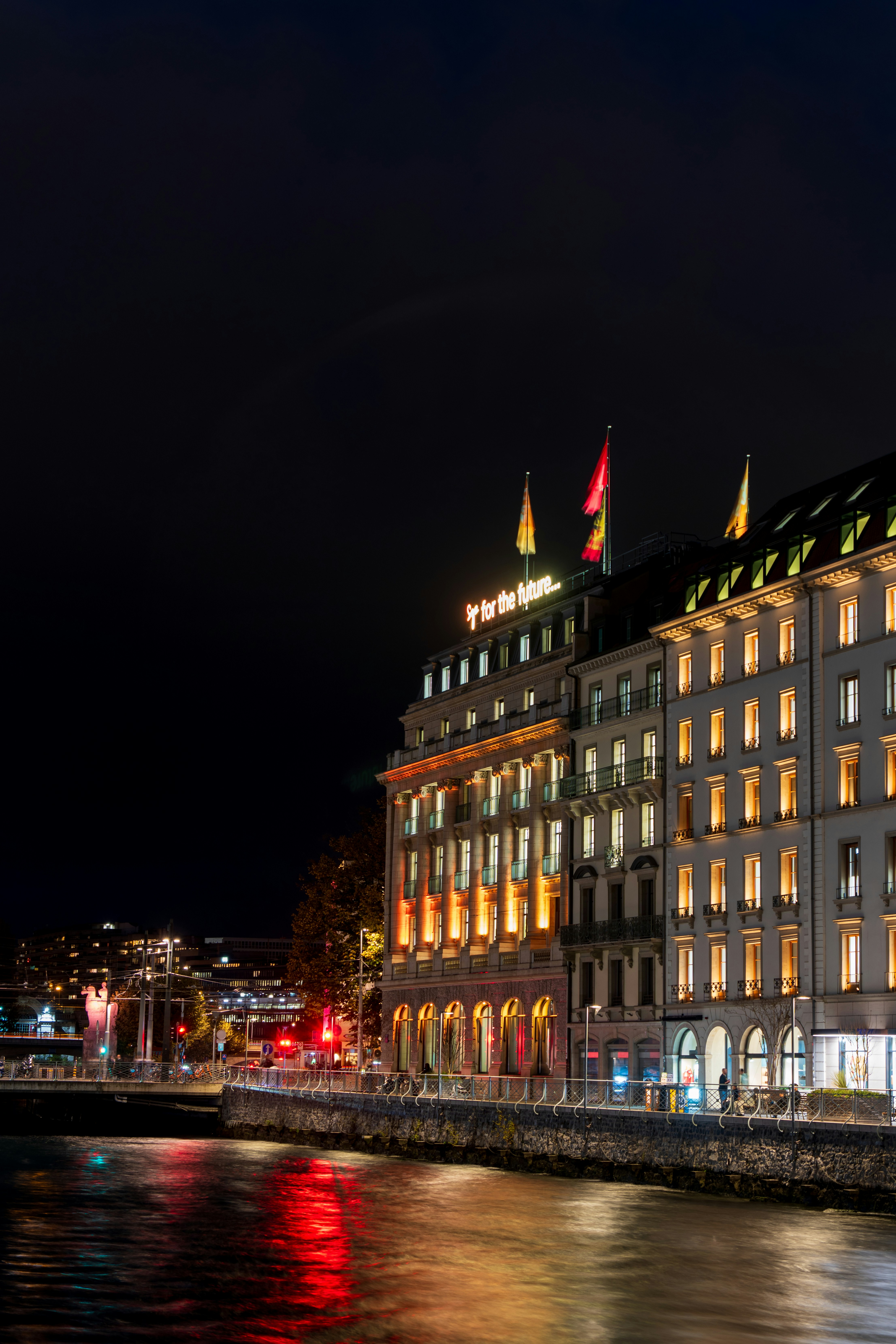 Un gran edificio se iluminaba por la noche junto a un cuerpo de agua
