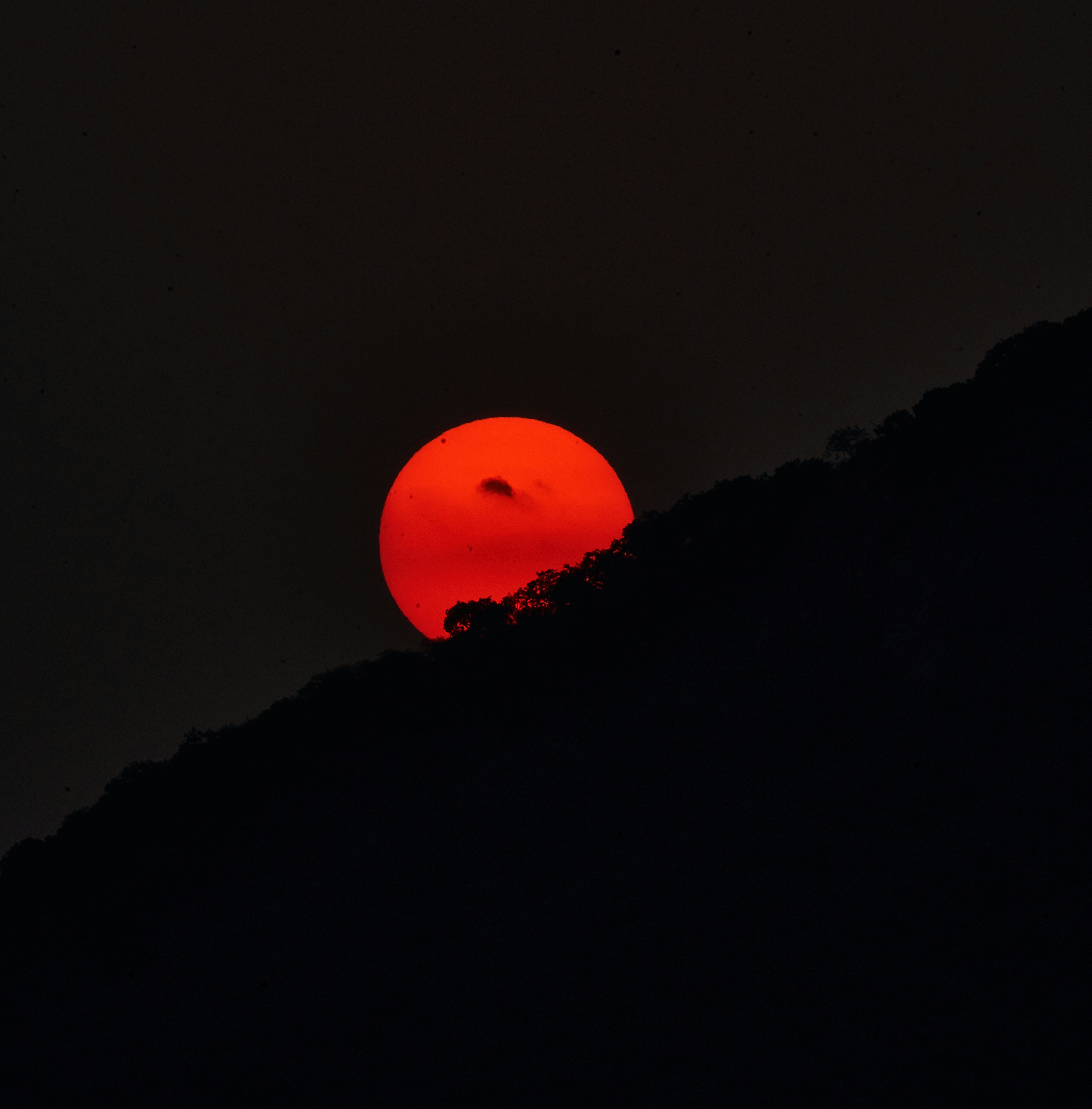 The sun is setting on a dark mountain