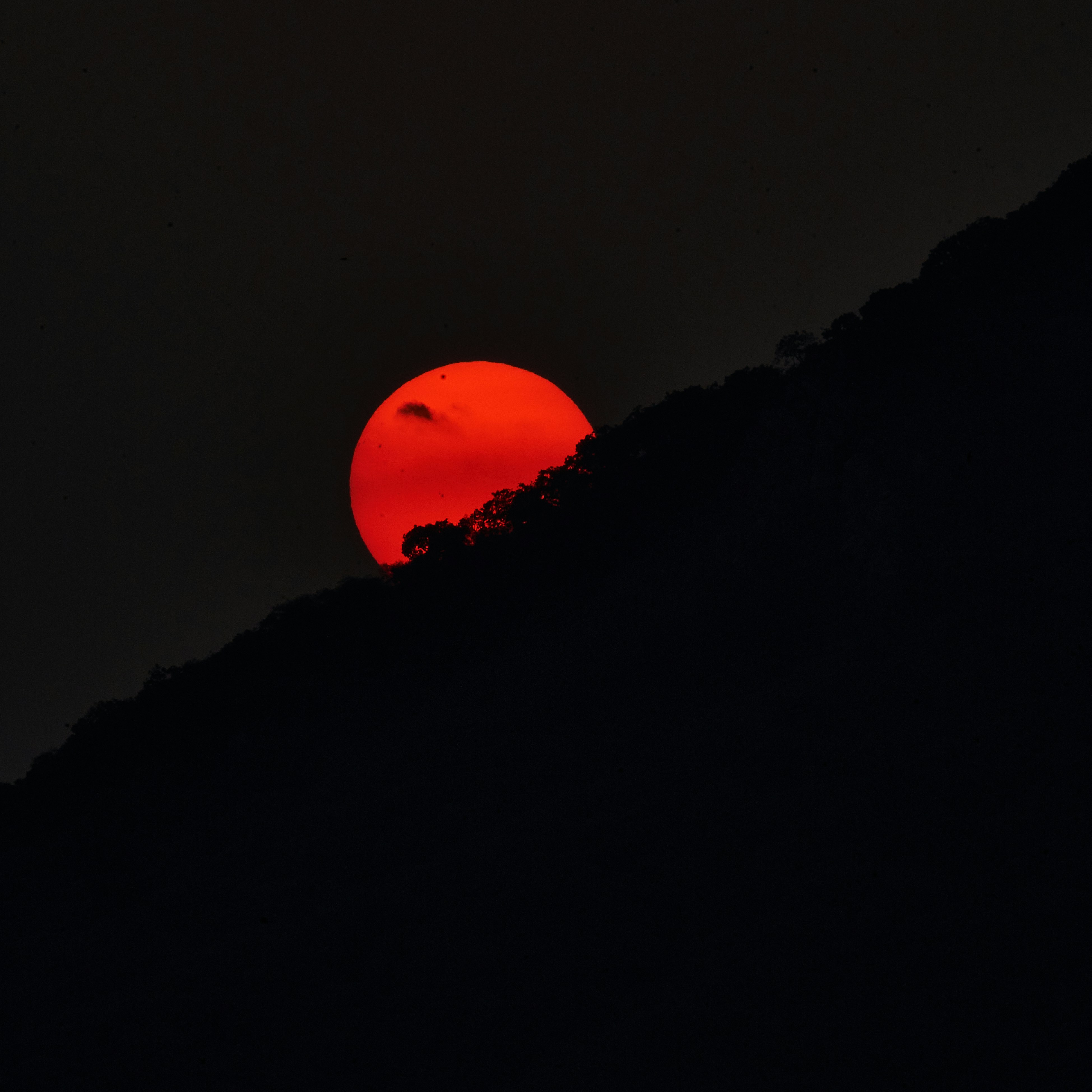 The sun is setting on a dark mountain
