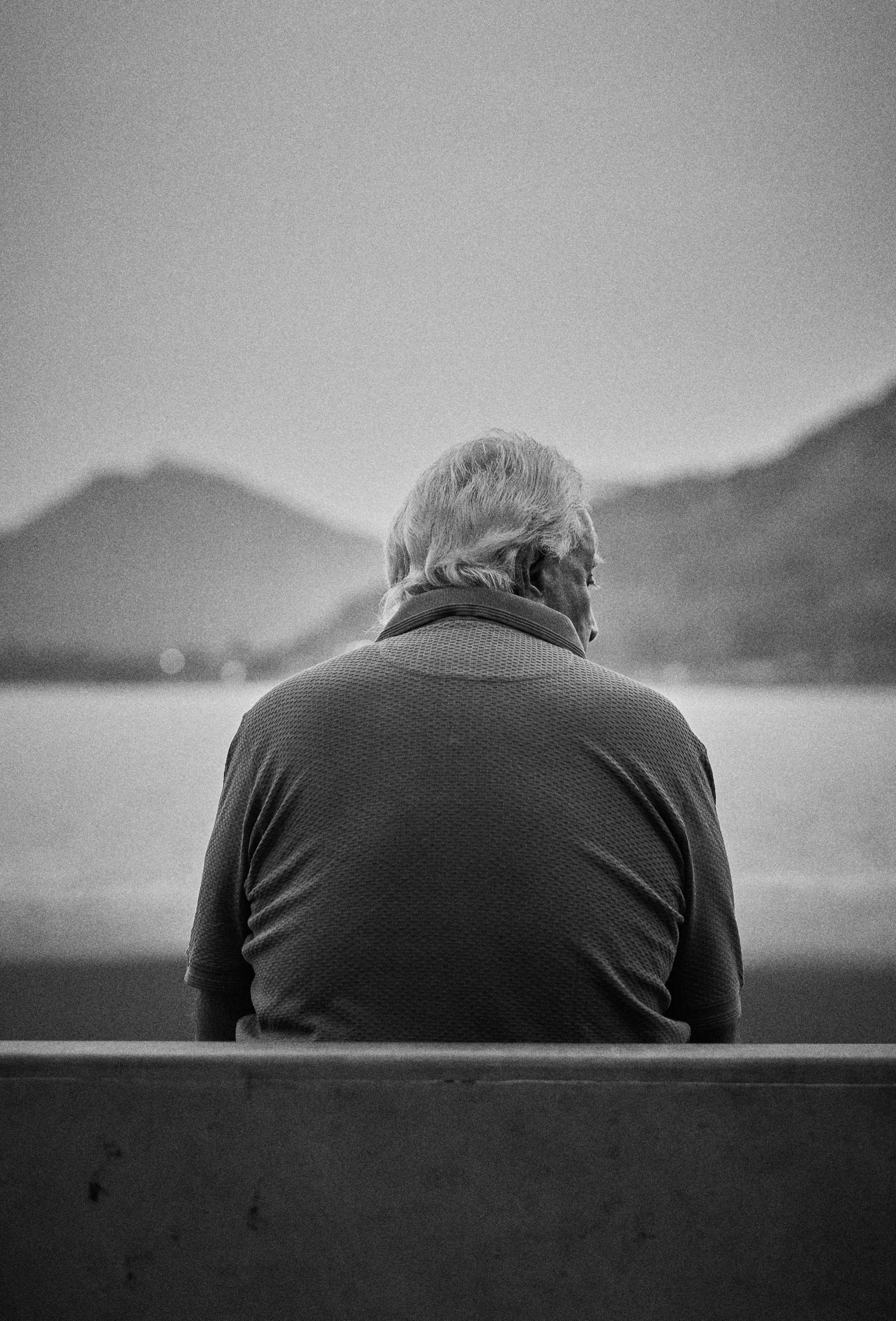 A black and white photo of a man sitting on a bench