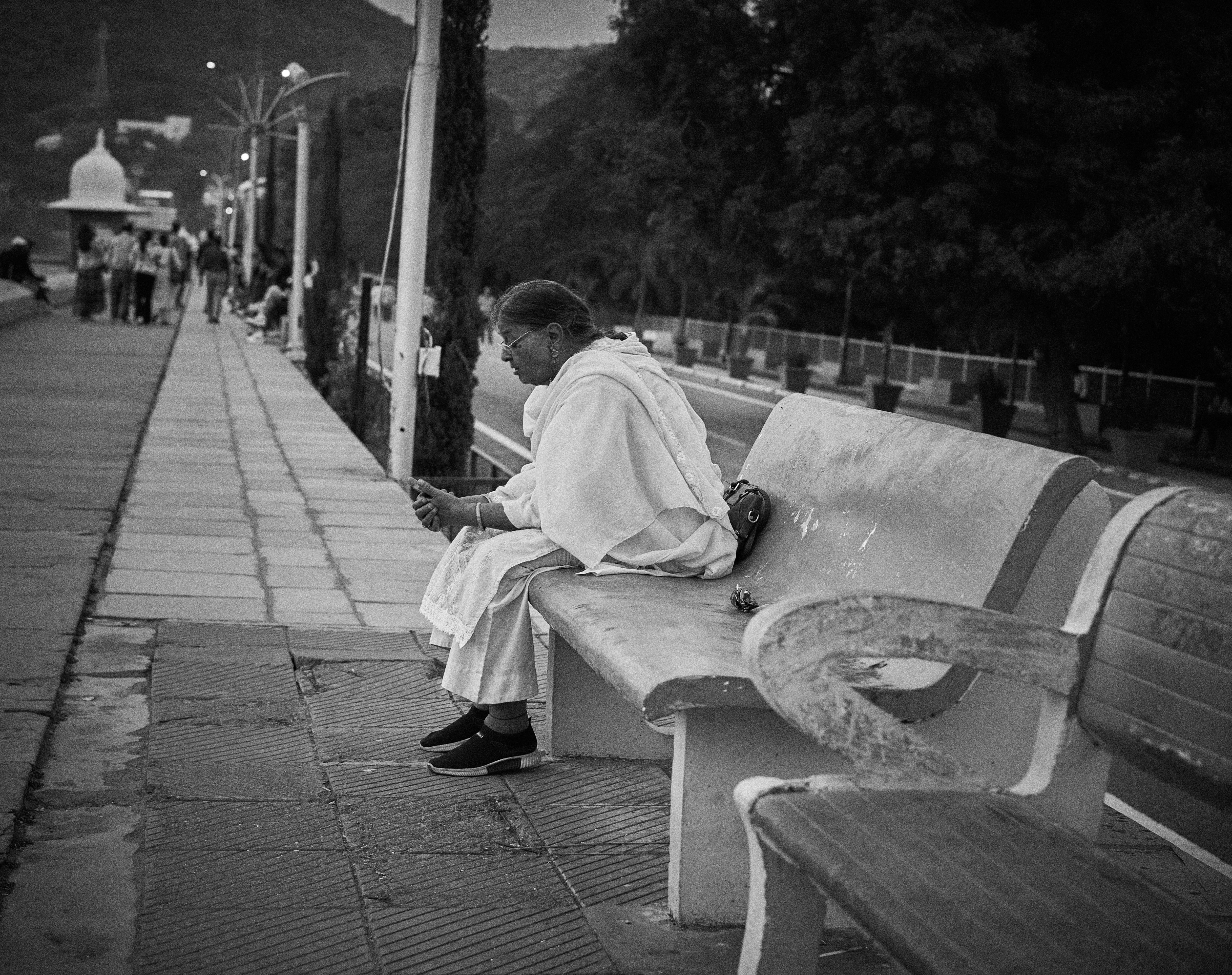 A black and white photo of a man sitting on a bench