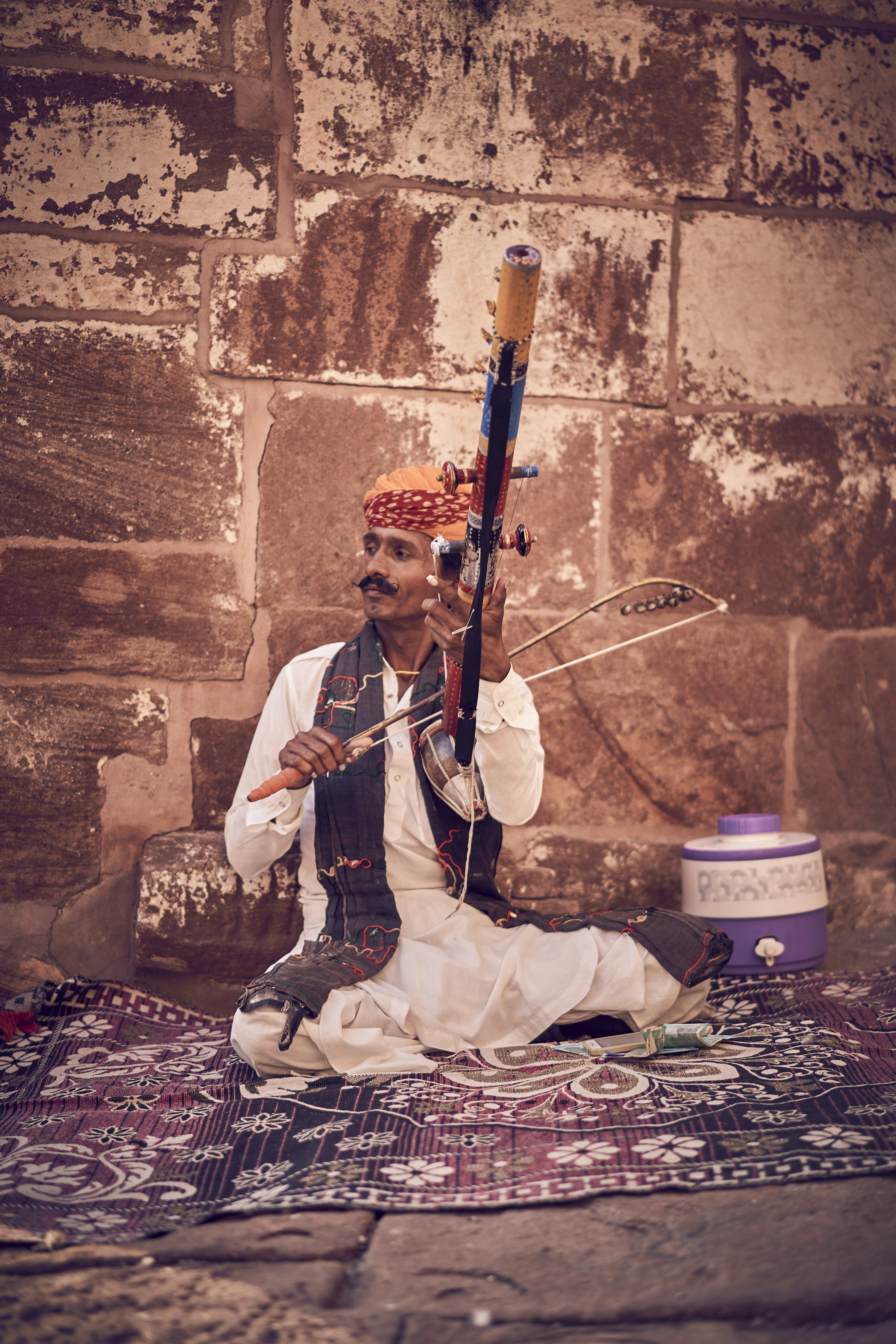 A man sitting on a rug holding a rifle