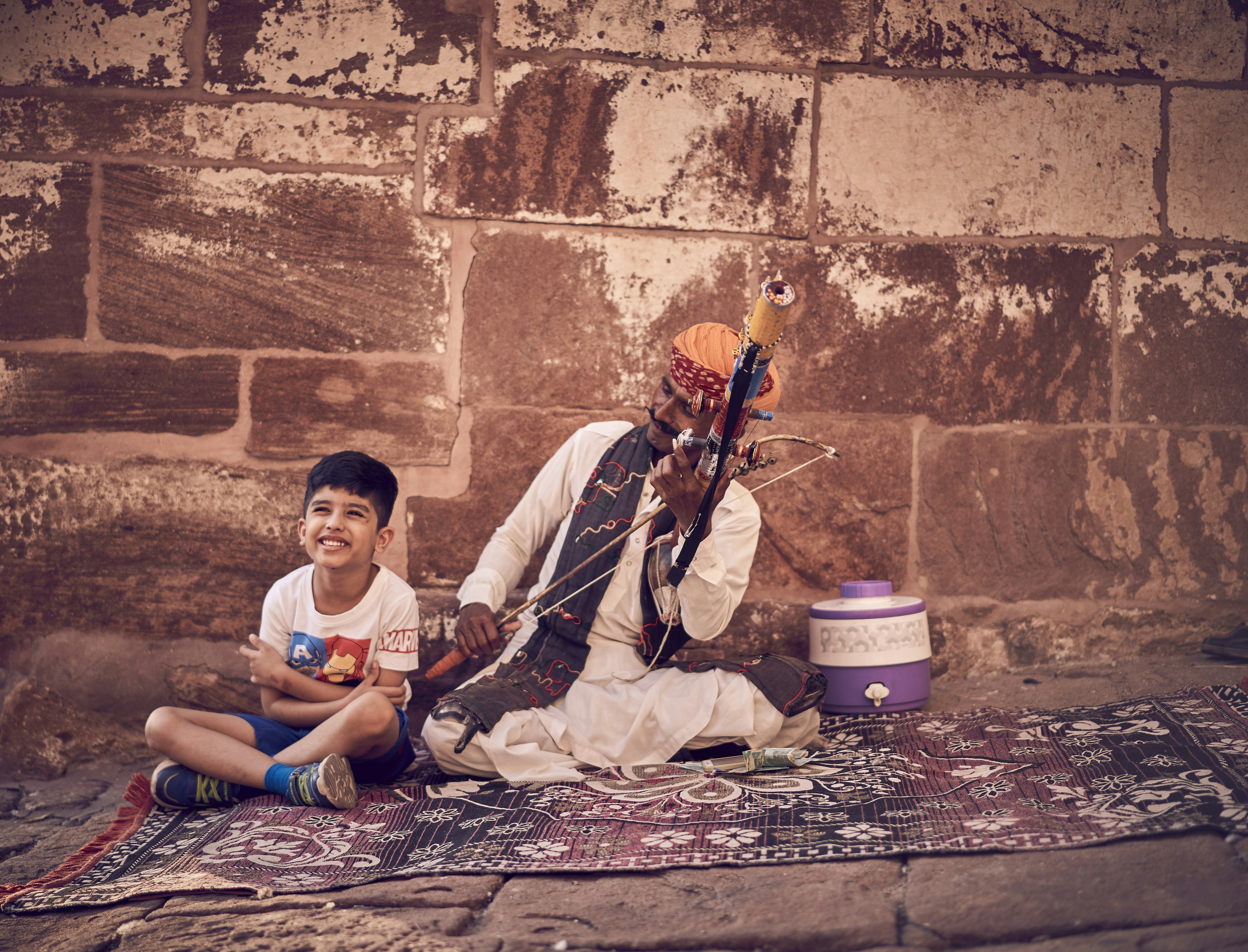 A man and a boy sitting on a rug