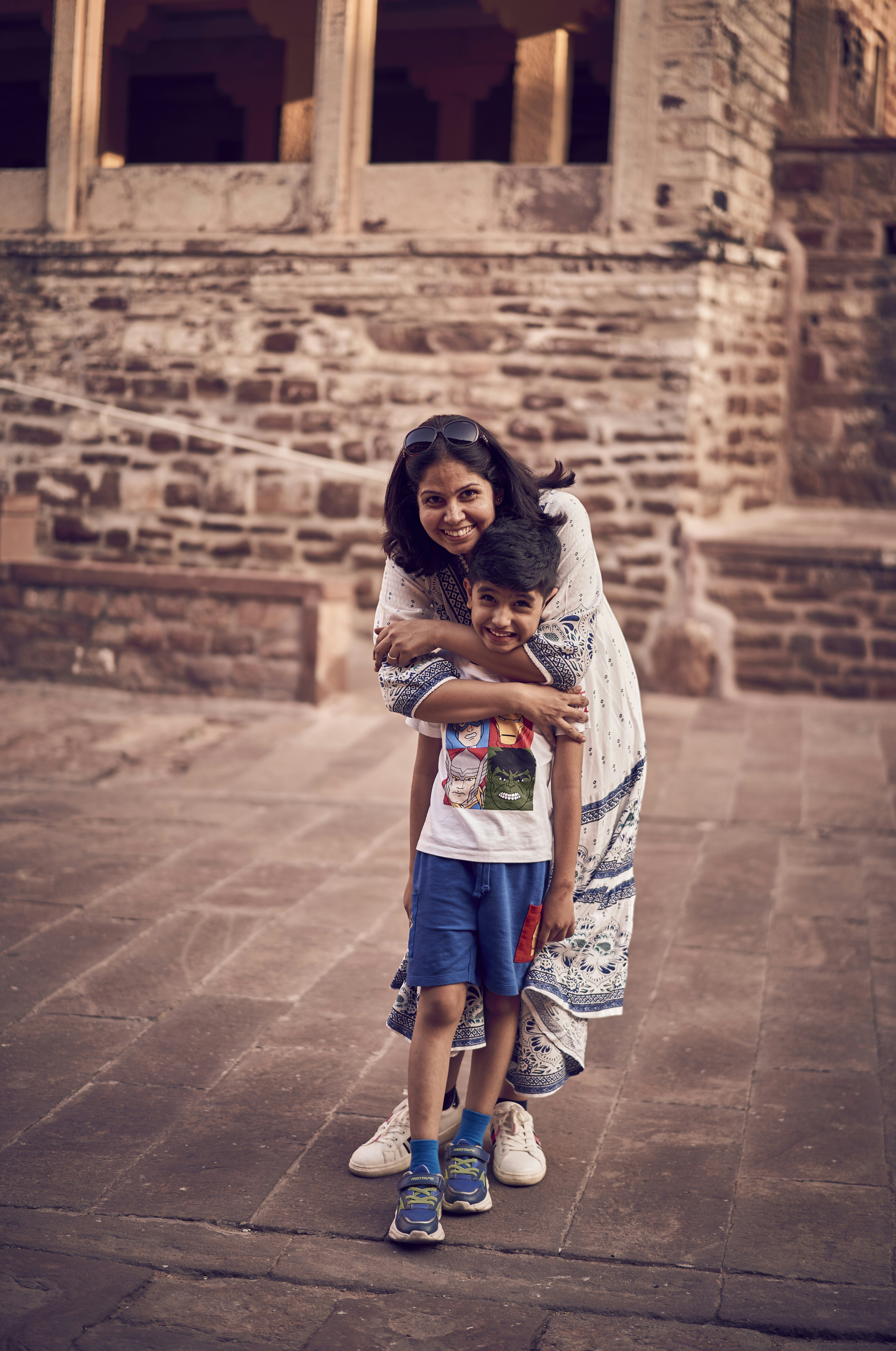 A woman is hugging a child in front of a building