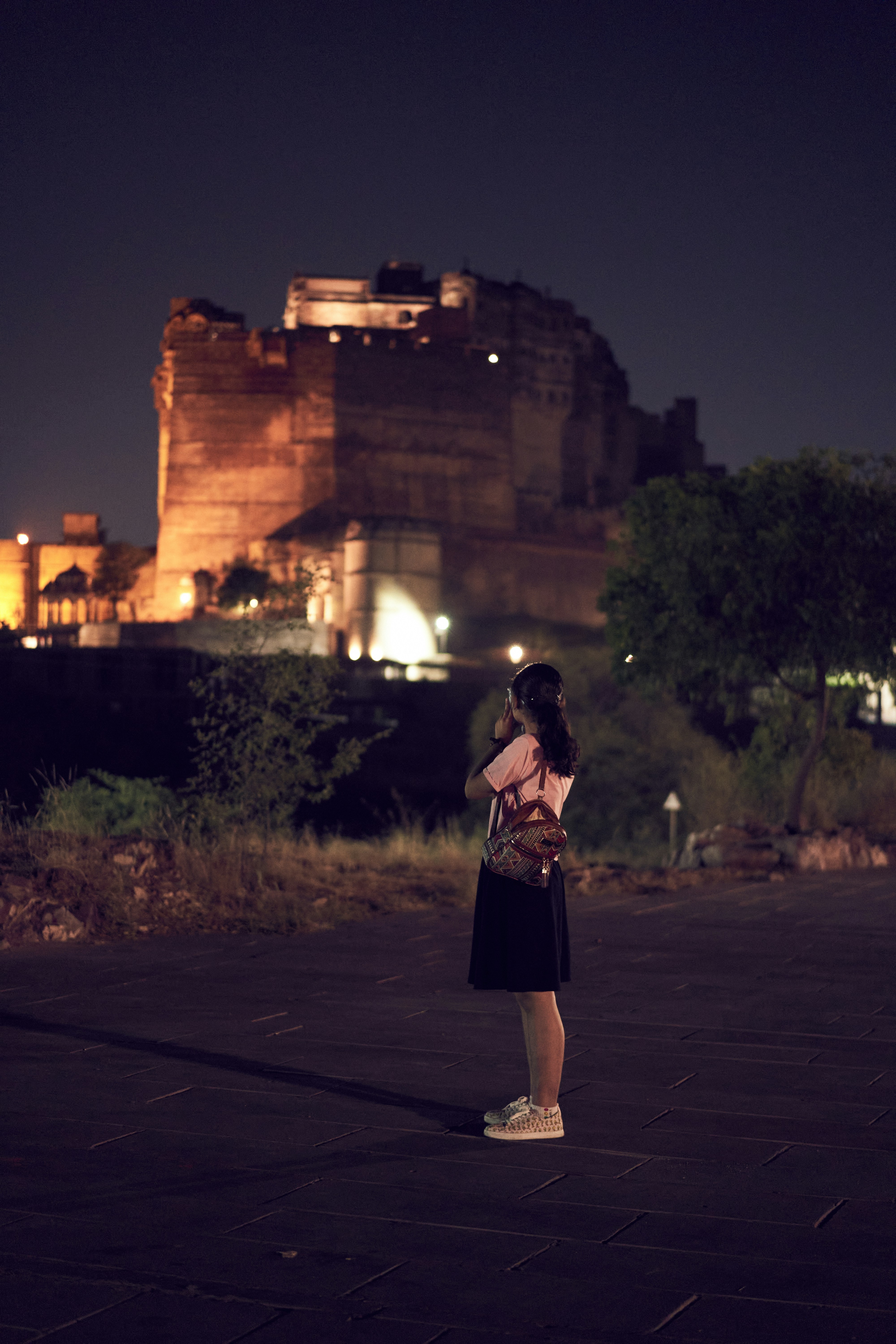 A woman standing in front of a castle at night