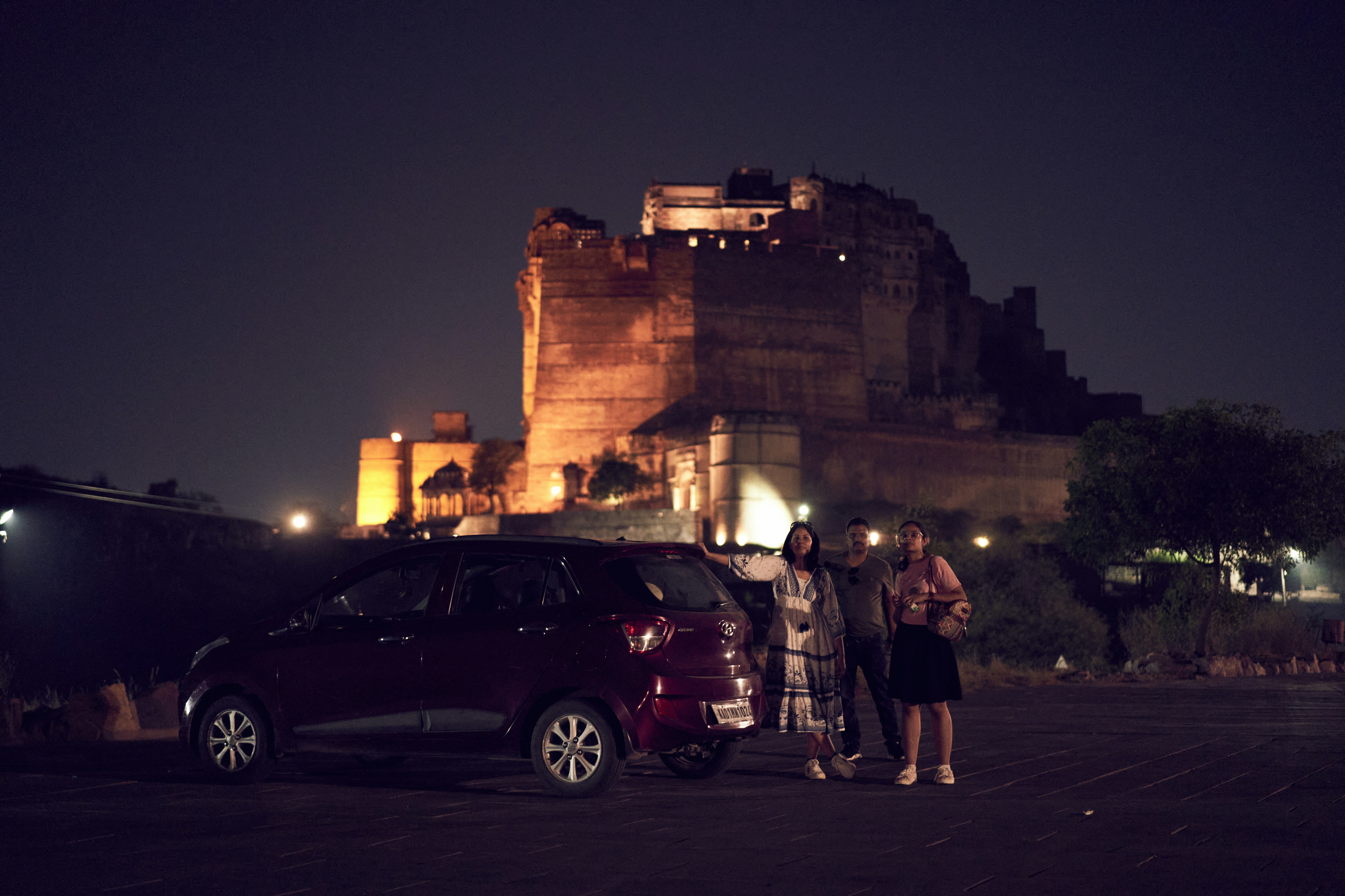 Two people standing next to a car in front of a castle