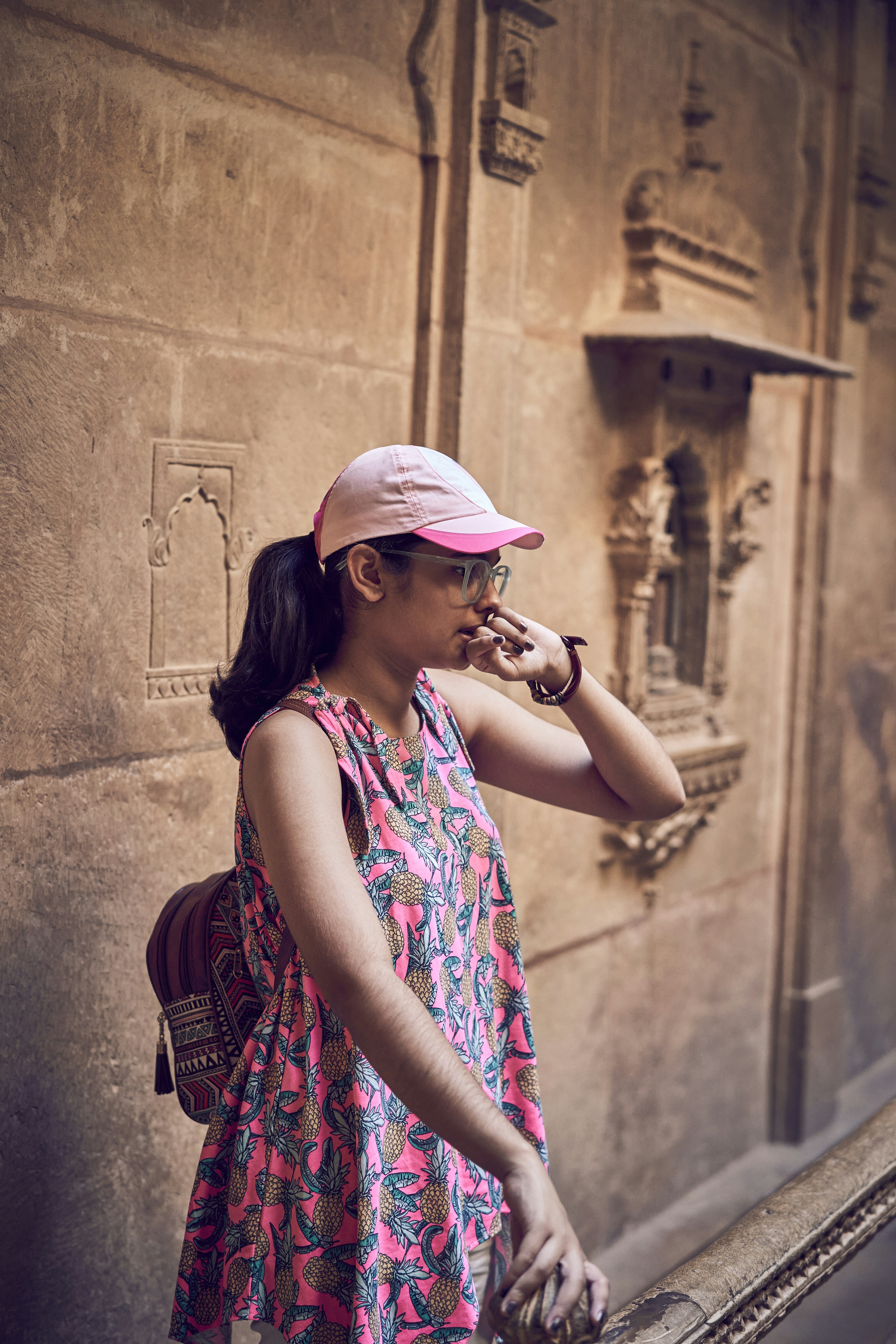 A woman in a pink hat leaning against a wall