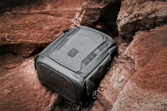 A black backpack sitting on top of a rock