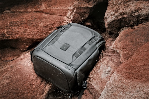 A black backpack sitting on top of a rock